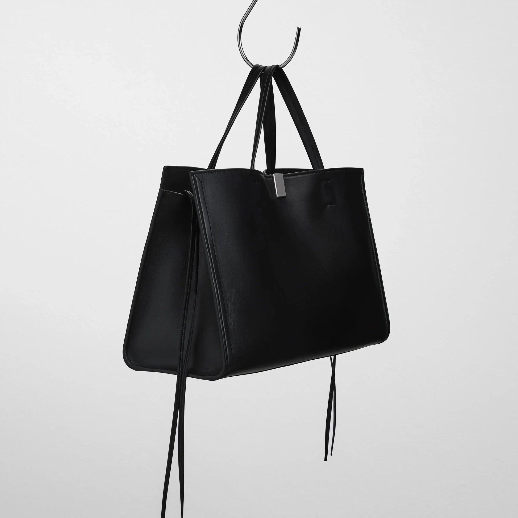 Side view of medium kit cabas in soft calf black leather with silver colour hardware.