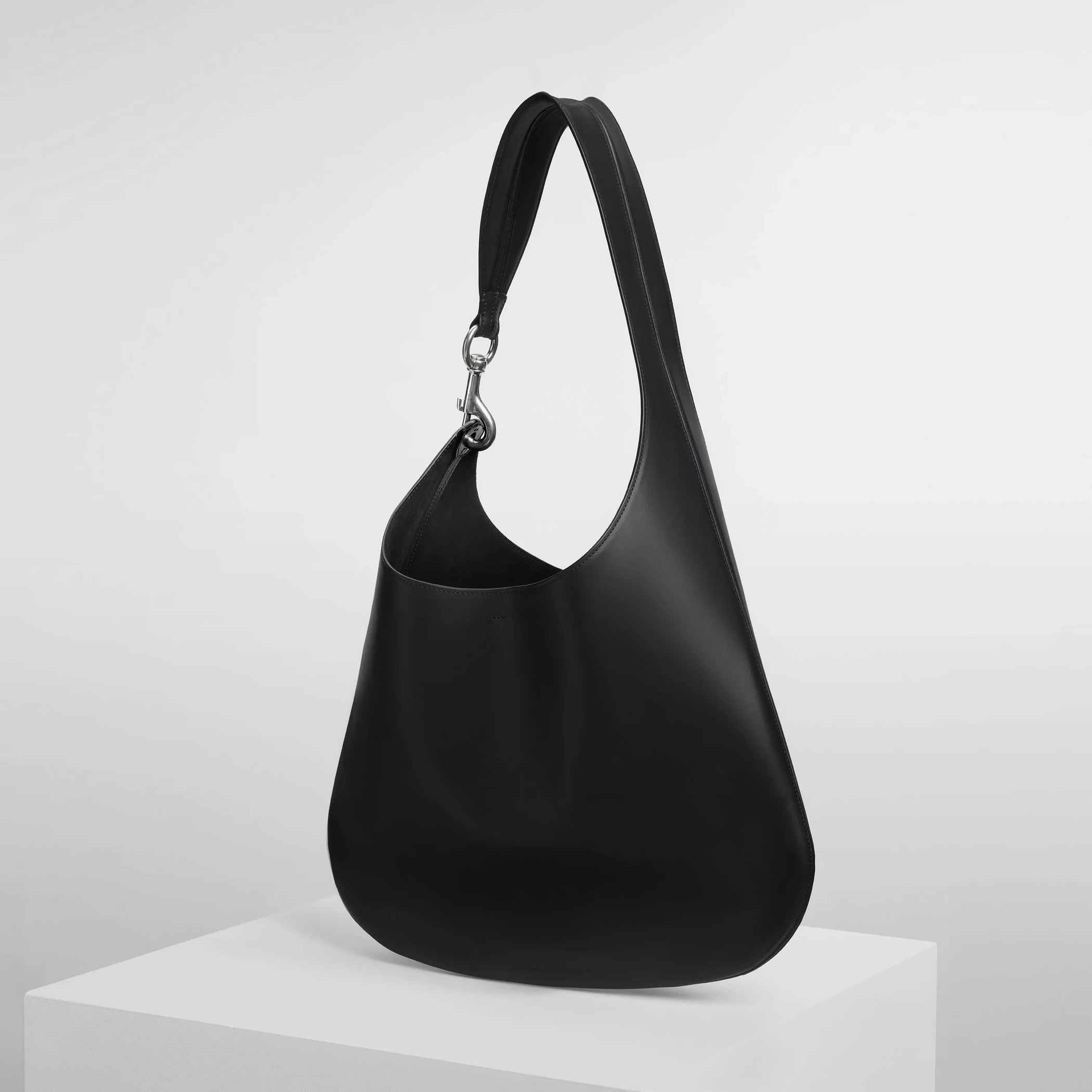 Angled side view of bean sling bag in black leather.