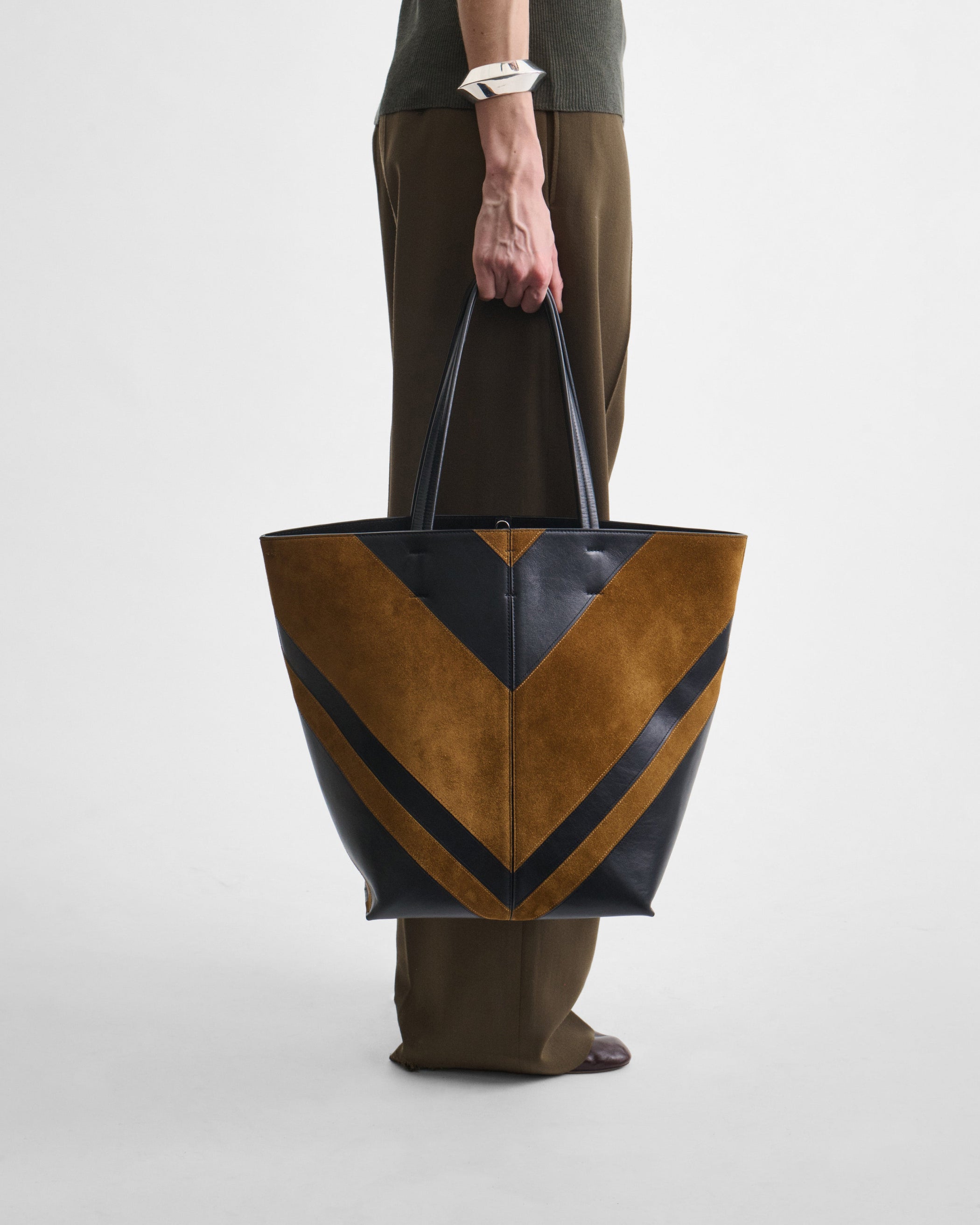 Model holding POT CABAS BAG in black leather and toffee suede