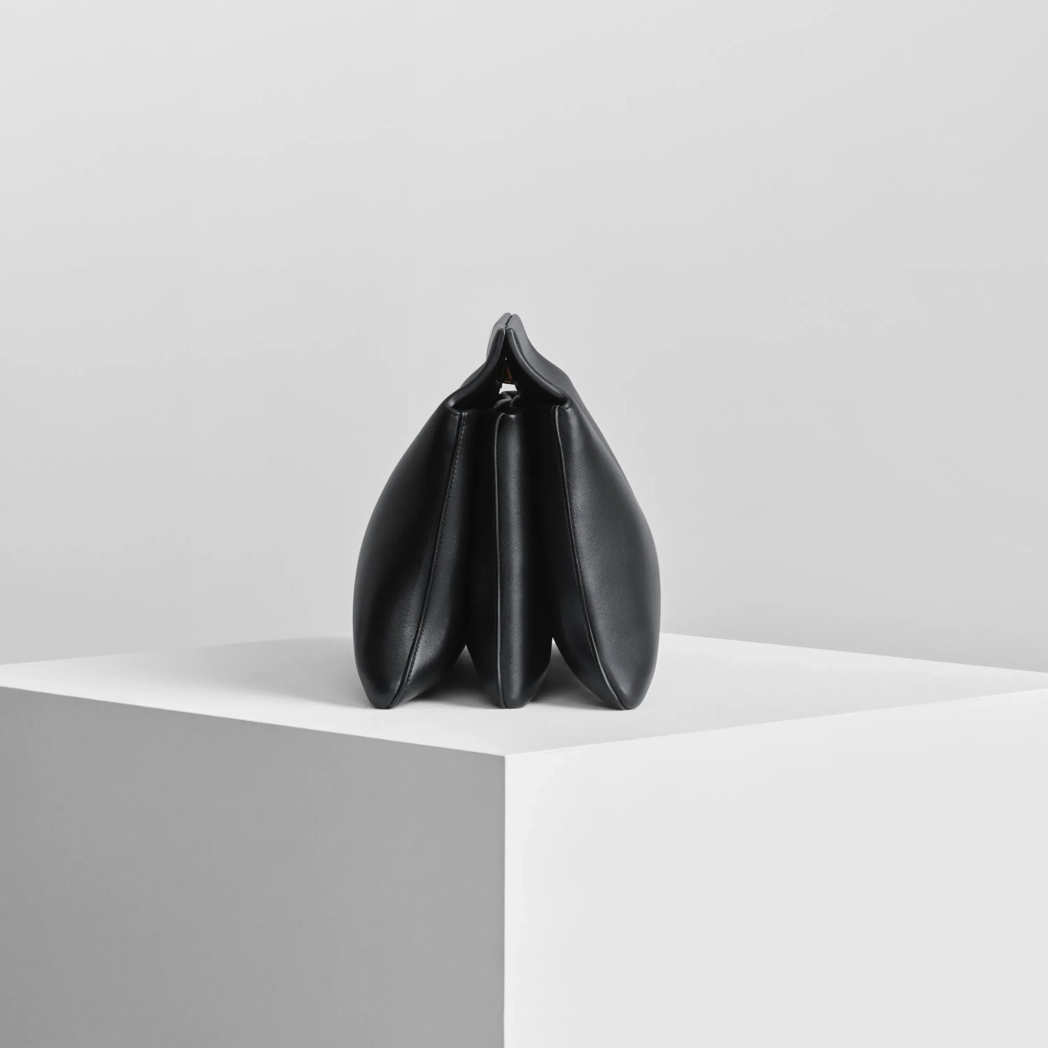 Side view of triplex clutch in black leather with gold.