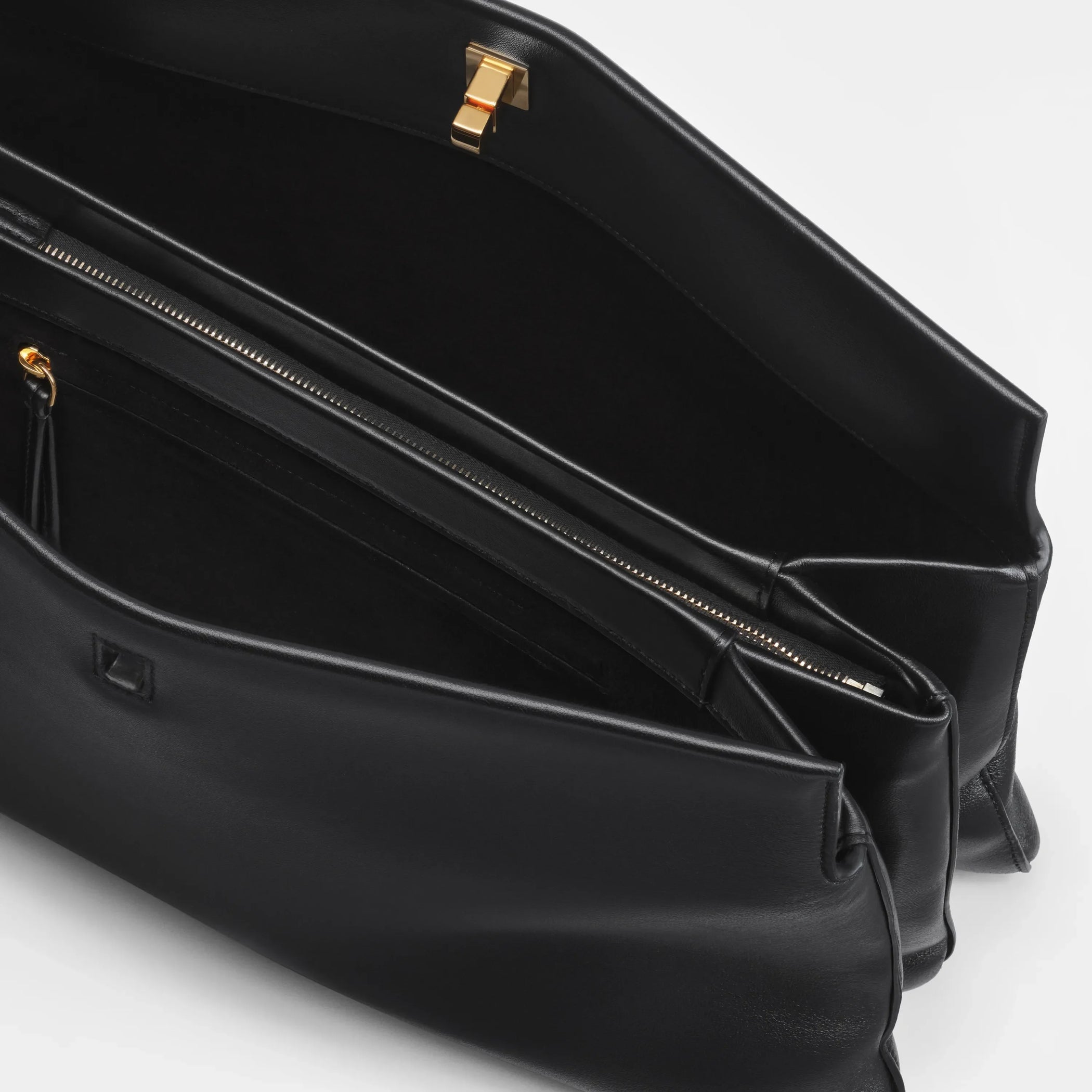 Close up detail view of triplex clutch in black leather with gold.
