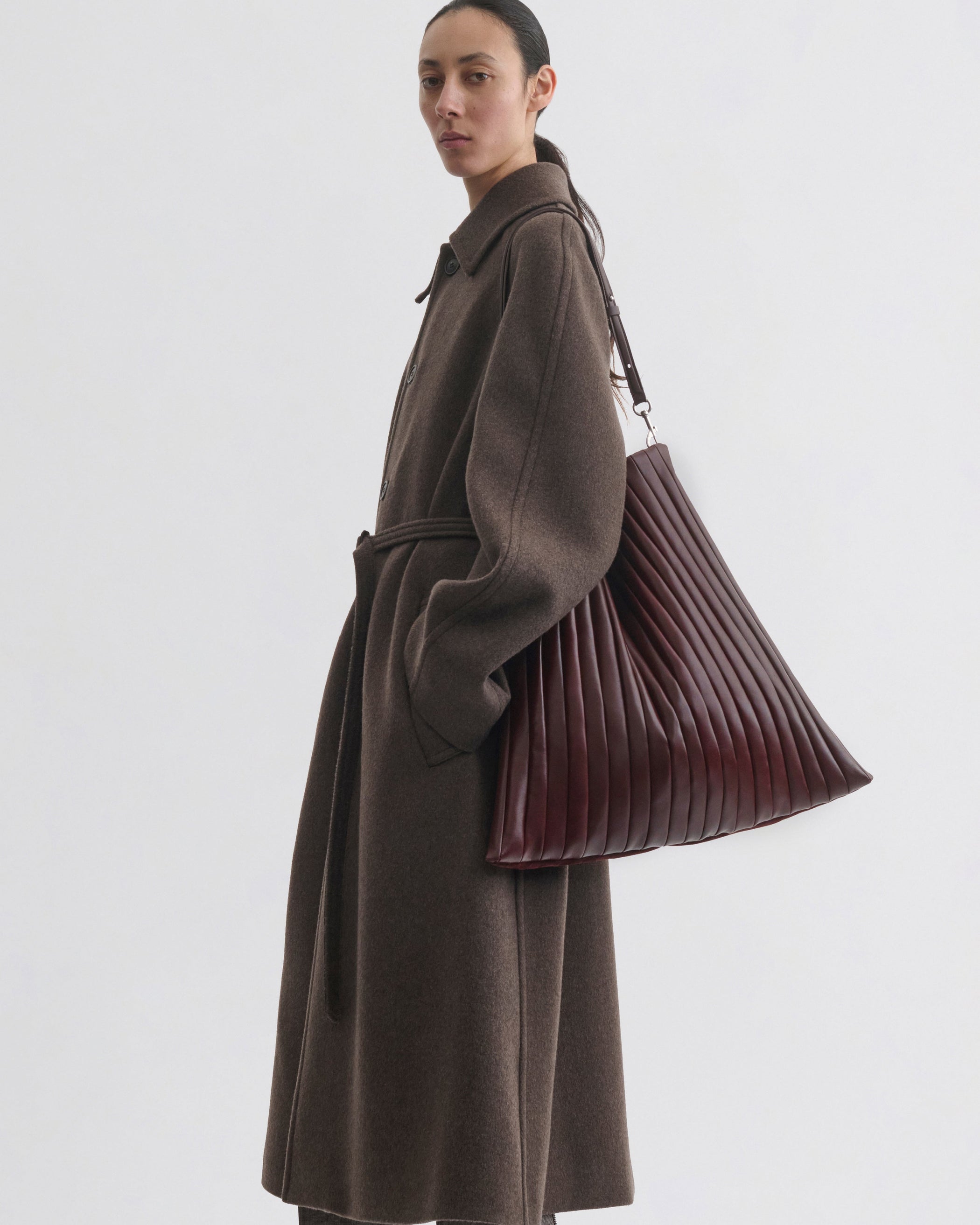 Model holding the ACCORDION BAG in oxblood leather