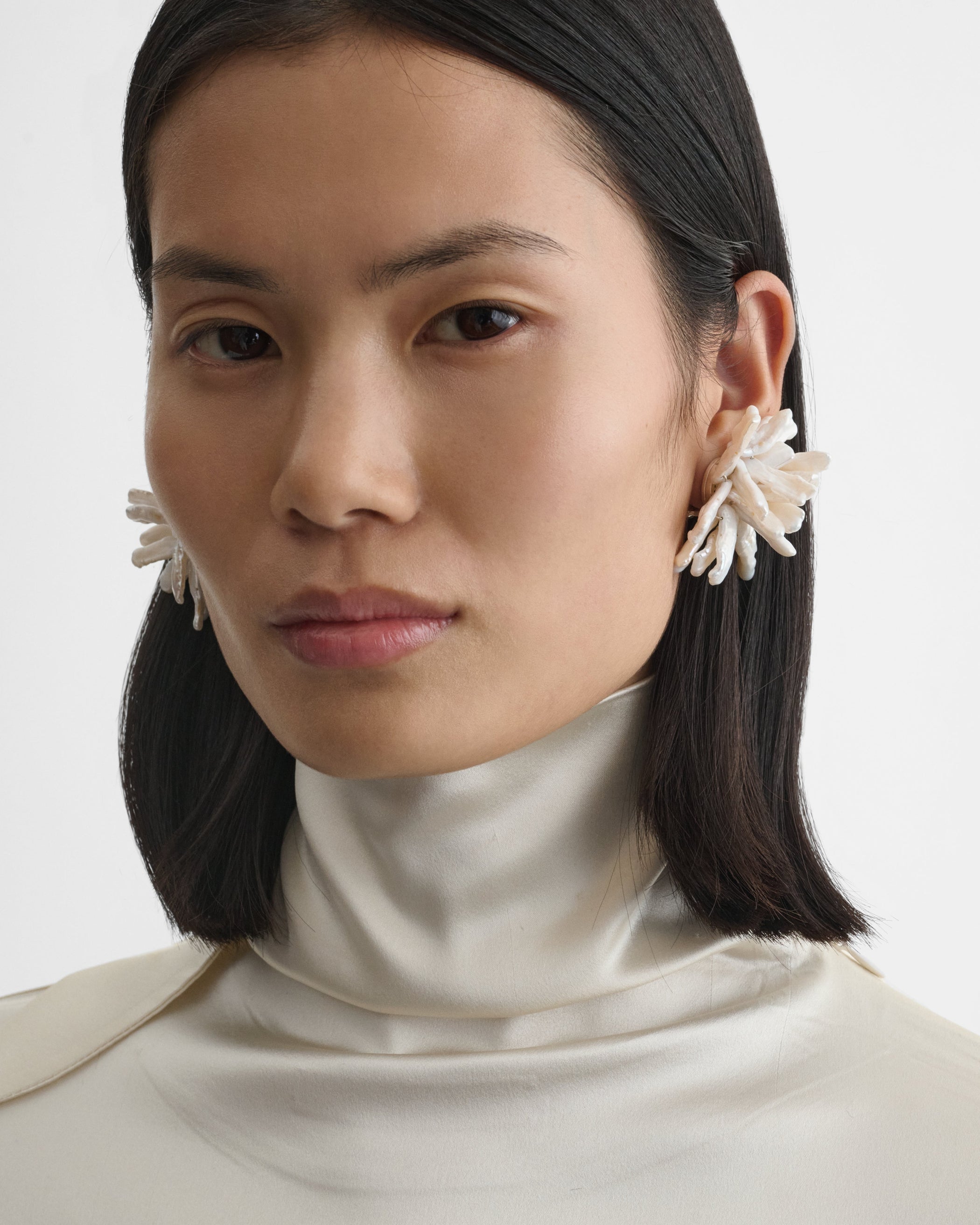 Front view of model wearing CLUSTER EARRINGS in silver cream resin