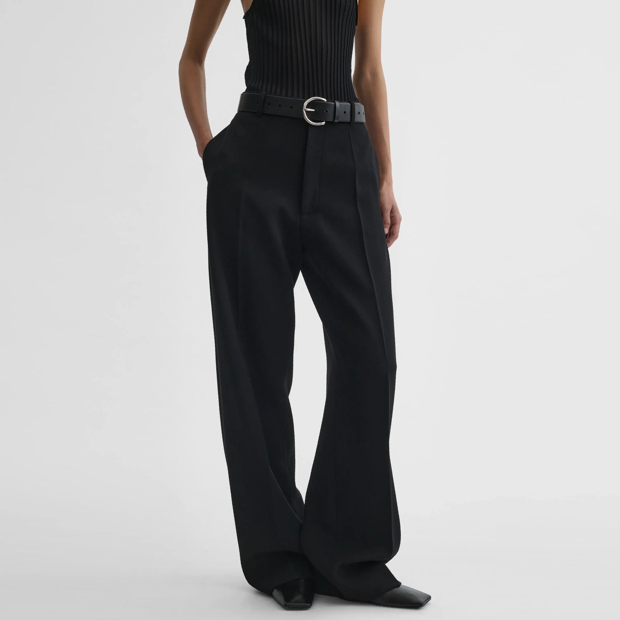 Front view of model wearing milanese trousers in black wool.