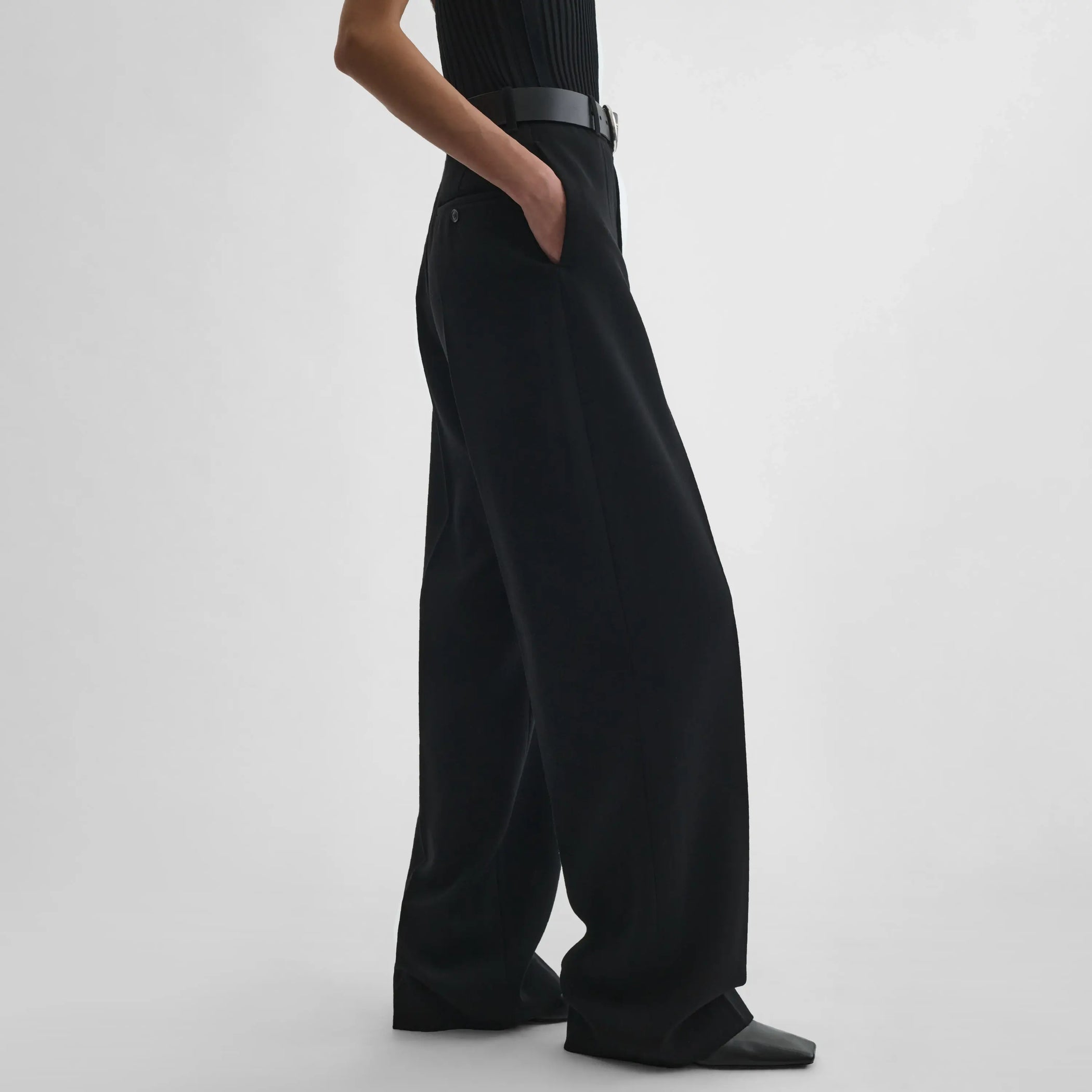 Side view of model wearing milanese trousers in black wool.