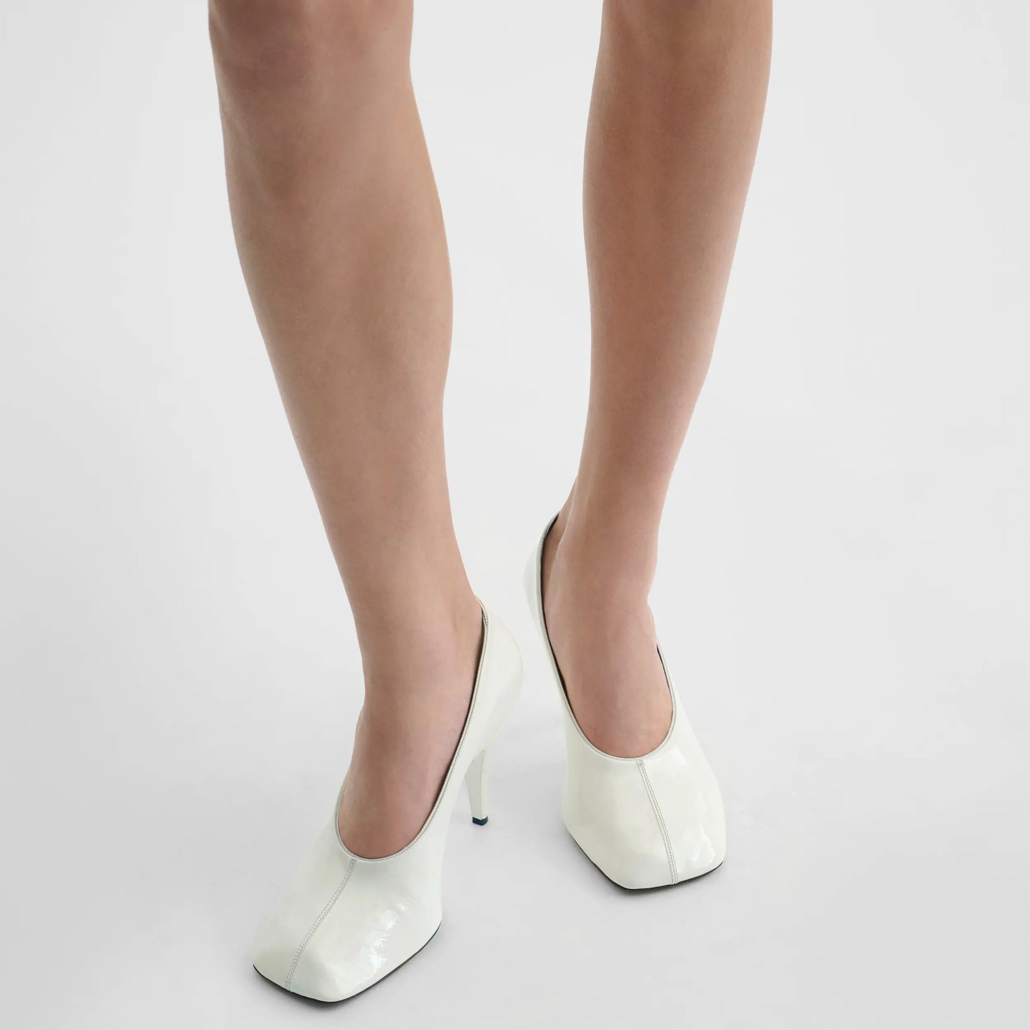 Model wearing soft pump 90 in white patent leather