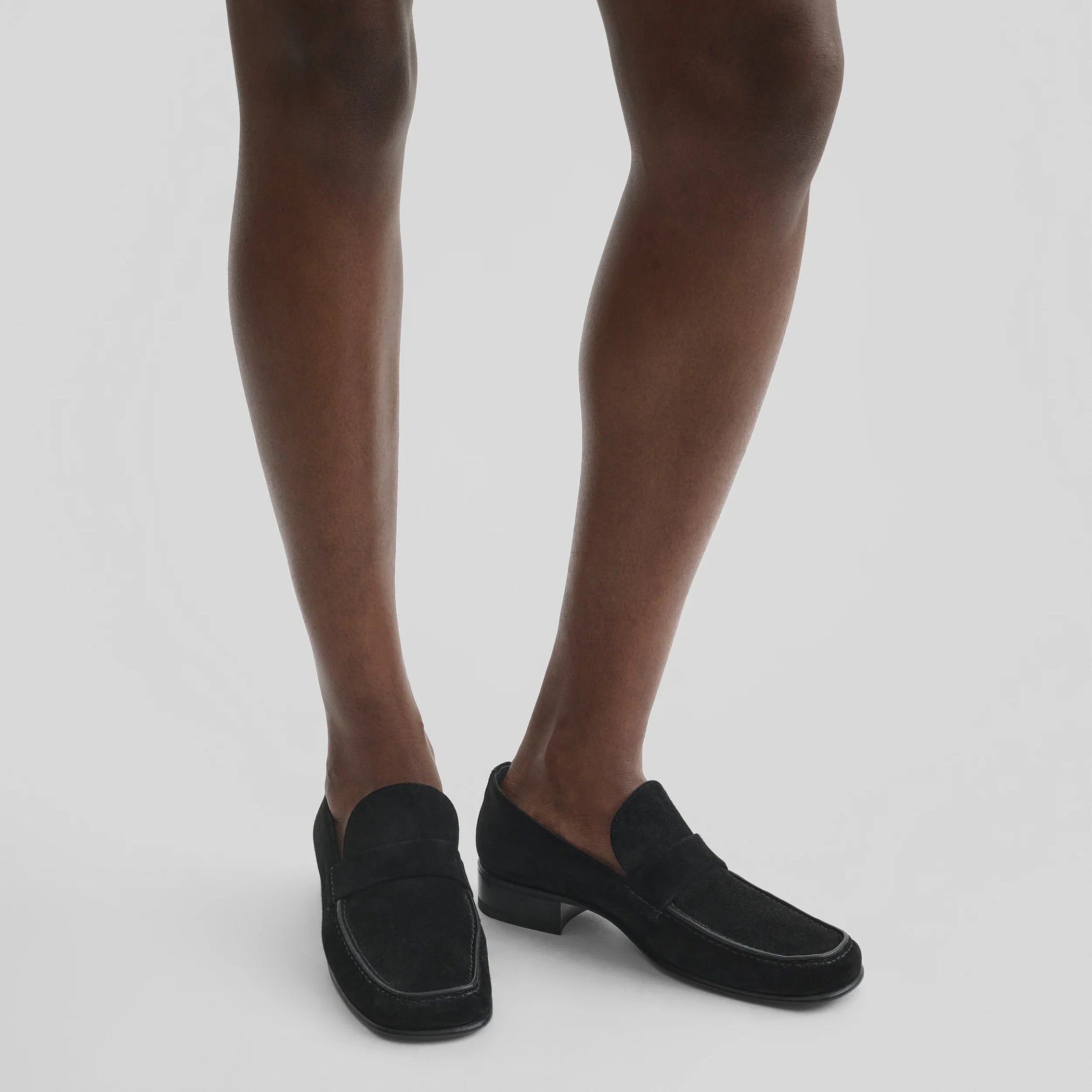 Model wearing man&#39;s loafer in black suede leather.