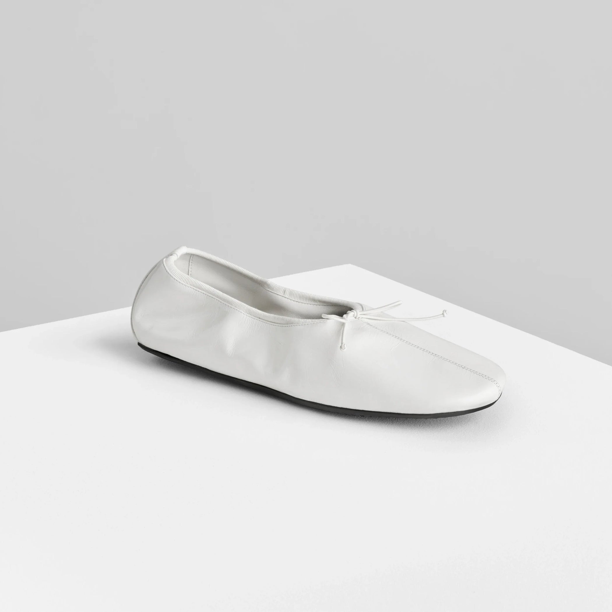 Side view of gathered flat in white leather.
