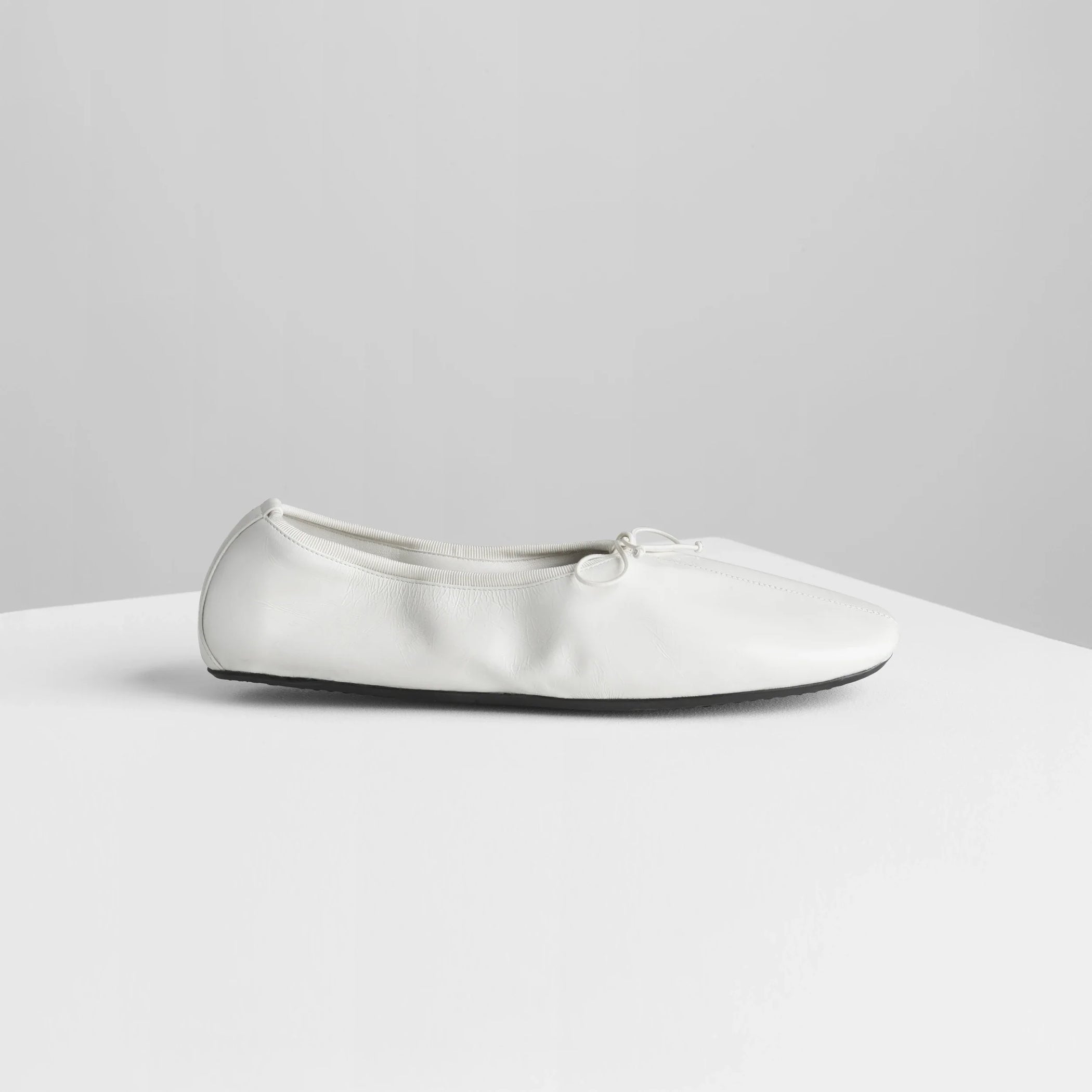 Side view of gathered flat in white leather.