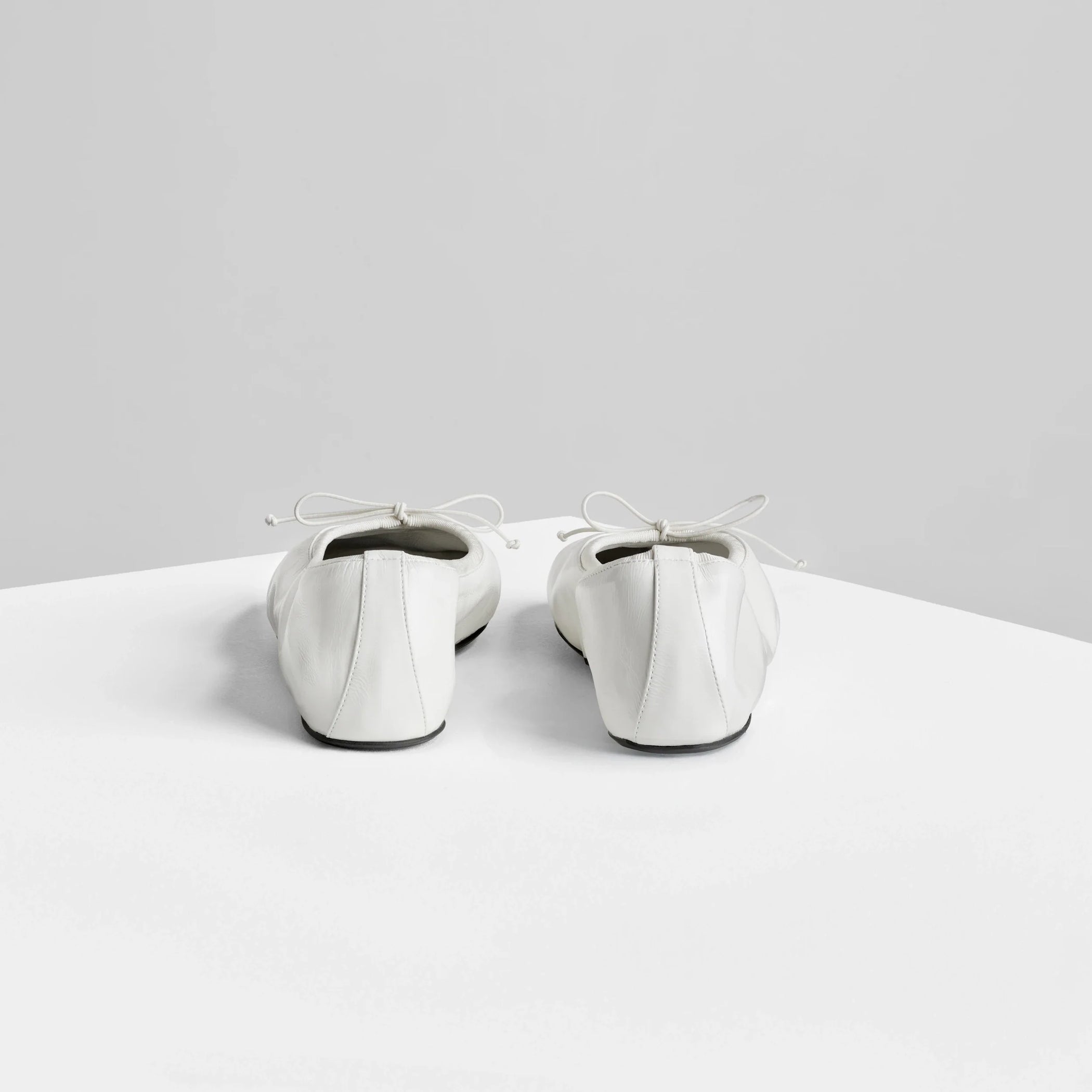 Back view of gathered flat in white leather.