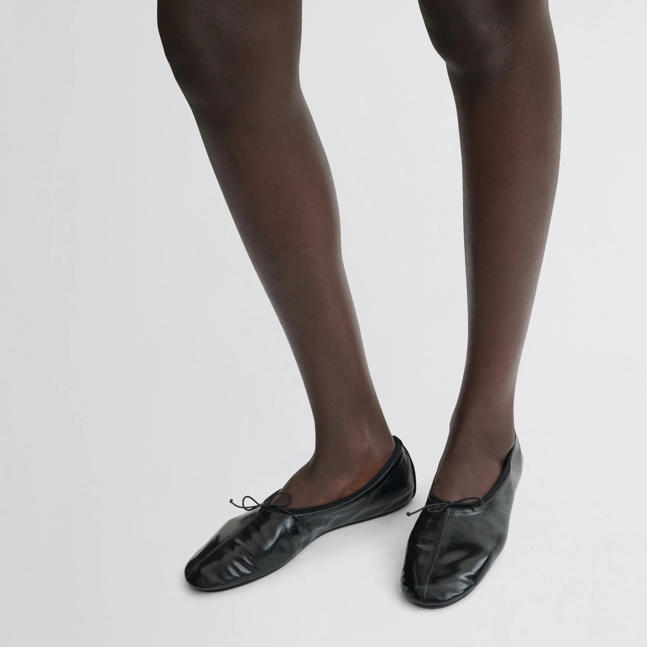 Front view of model wearing gathered flat in black leather.