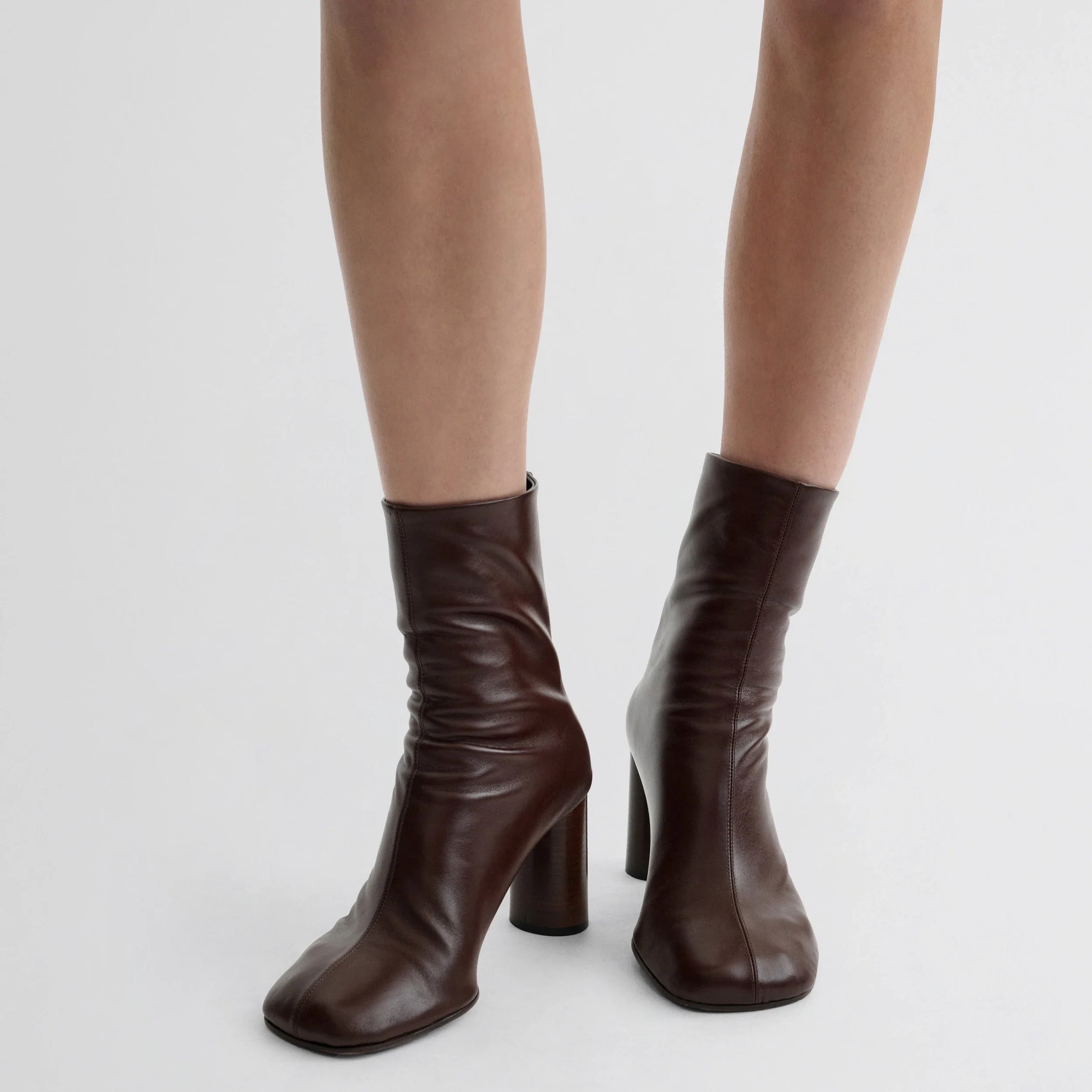 Front view of model wearing tug ankle boot in plum brown leather.