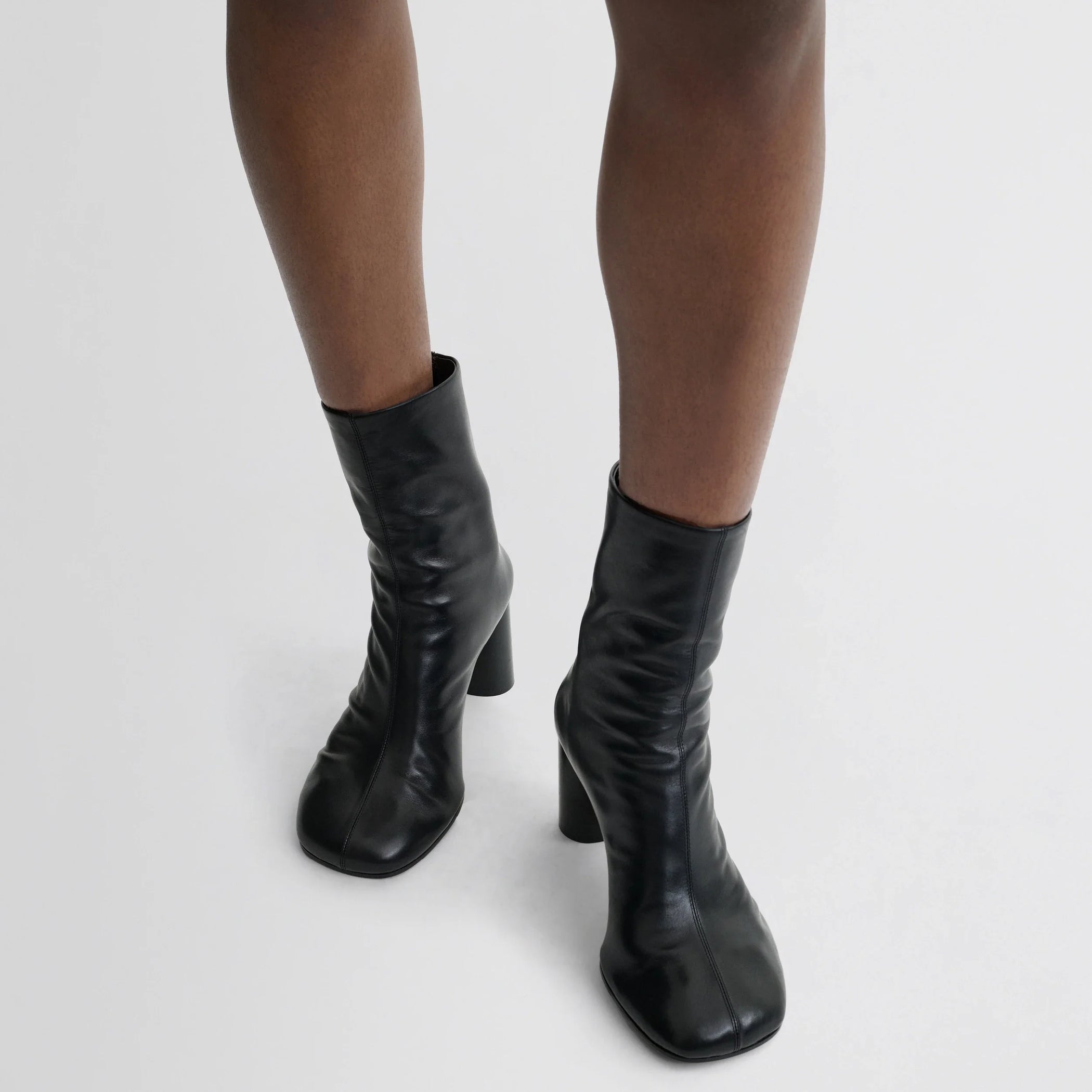 Front view of model wearing tug ankle boot in black leather.