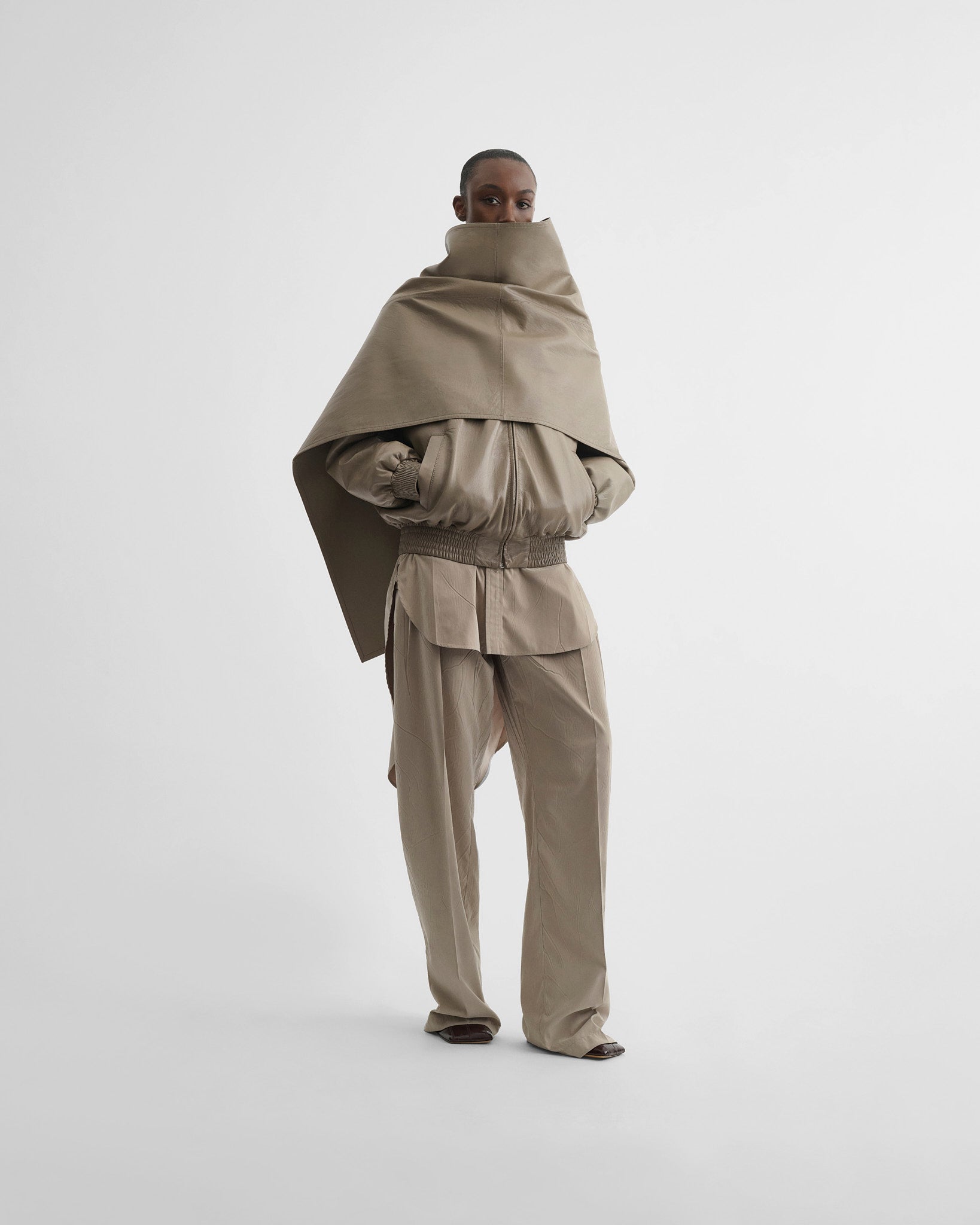 Front view of model wearing jacket with attachable scarf in mastic leather