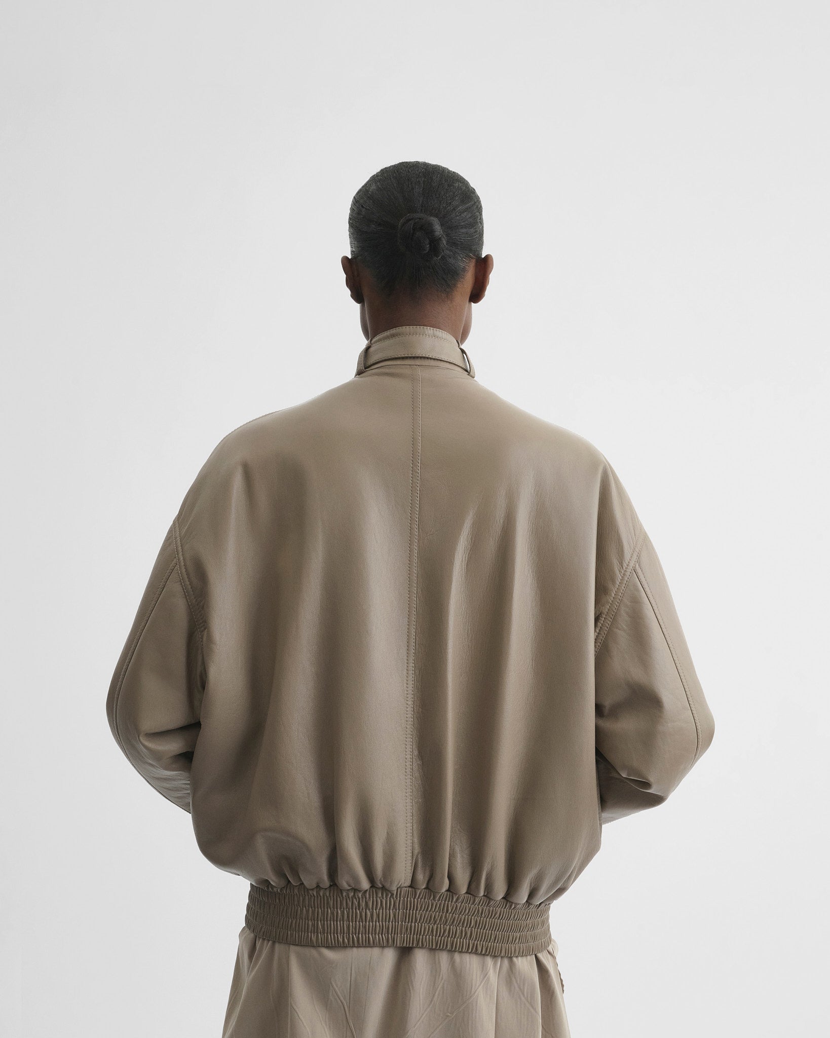 Back view of model wearing jacket with attachable scarf in mastic leather