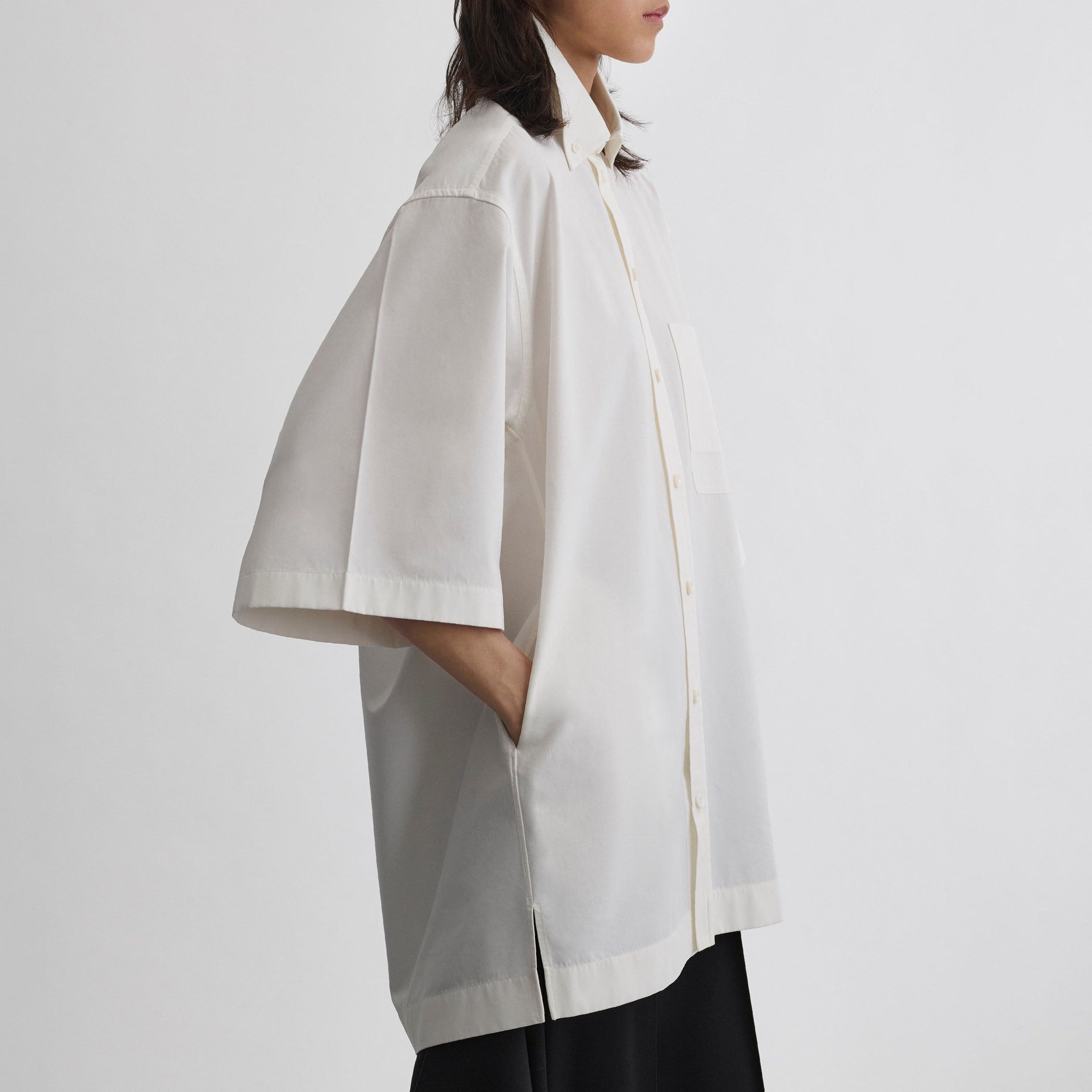Side view of model wearing UNIFORM SHIRT in white cotton