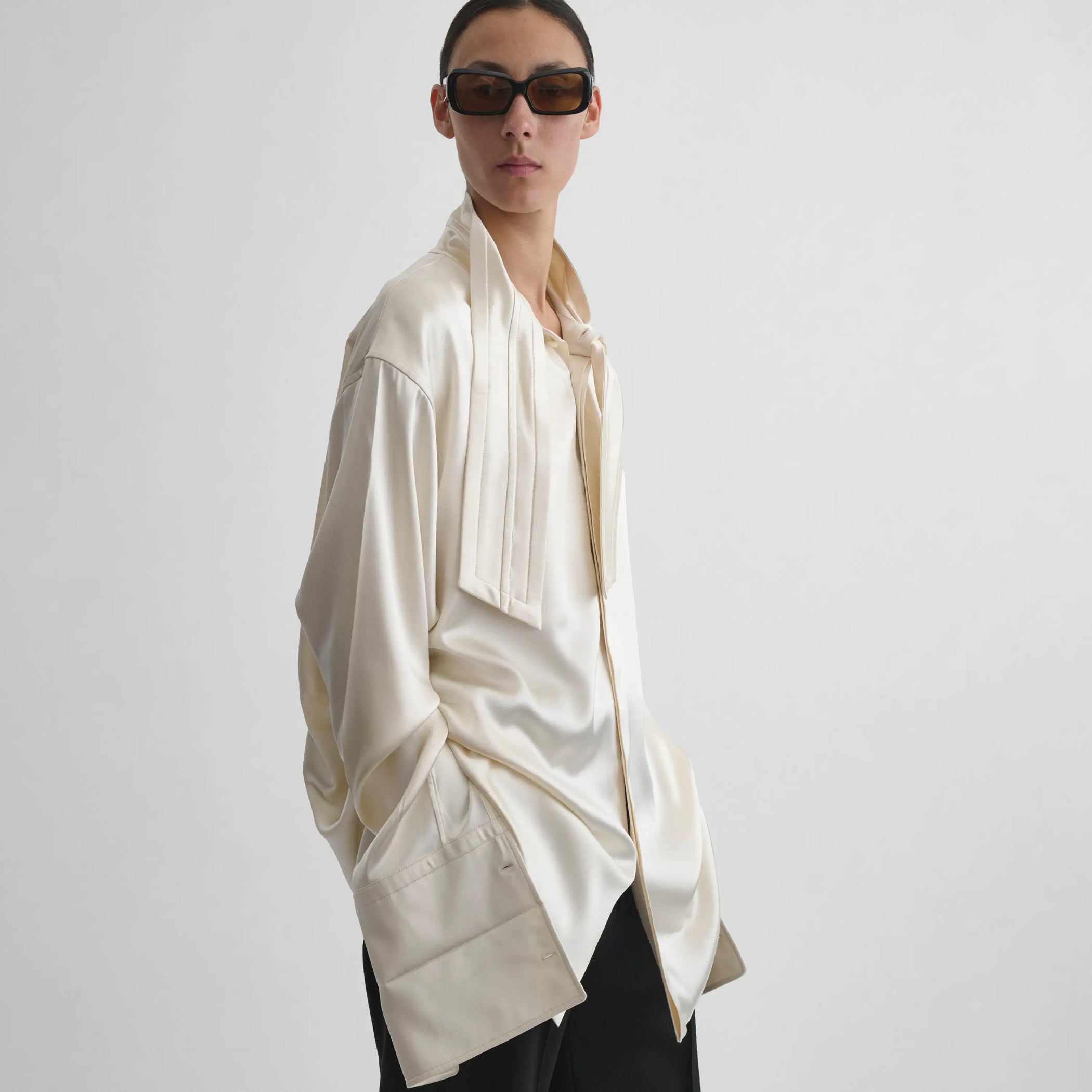 Angled view of model wearing Tie Neck Shirt in cream.