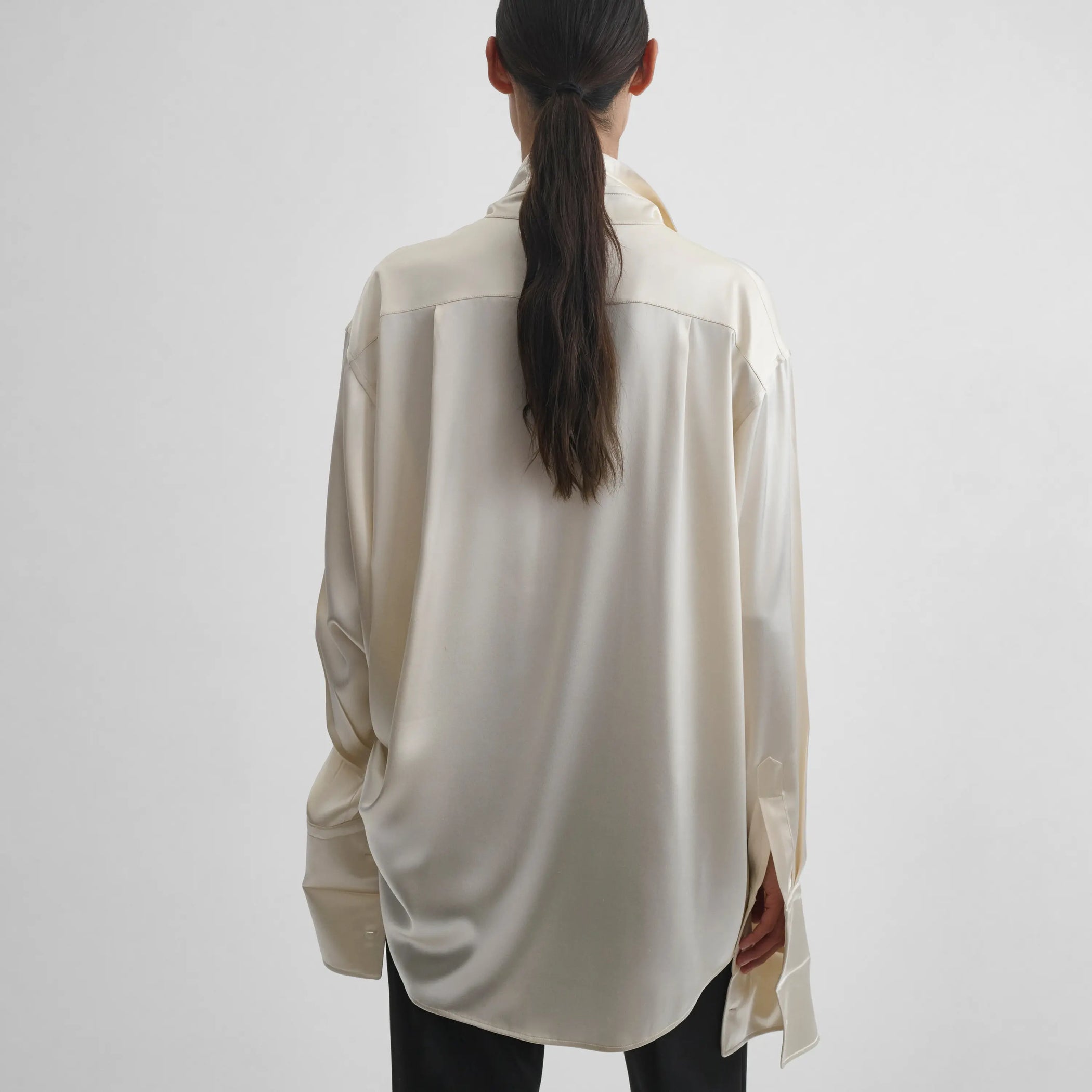 Back view of model wearing Tie Neck Shirt in cream.
