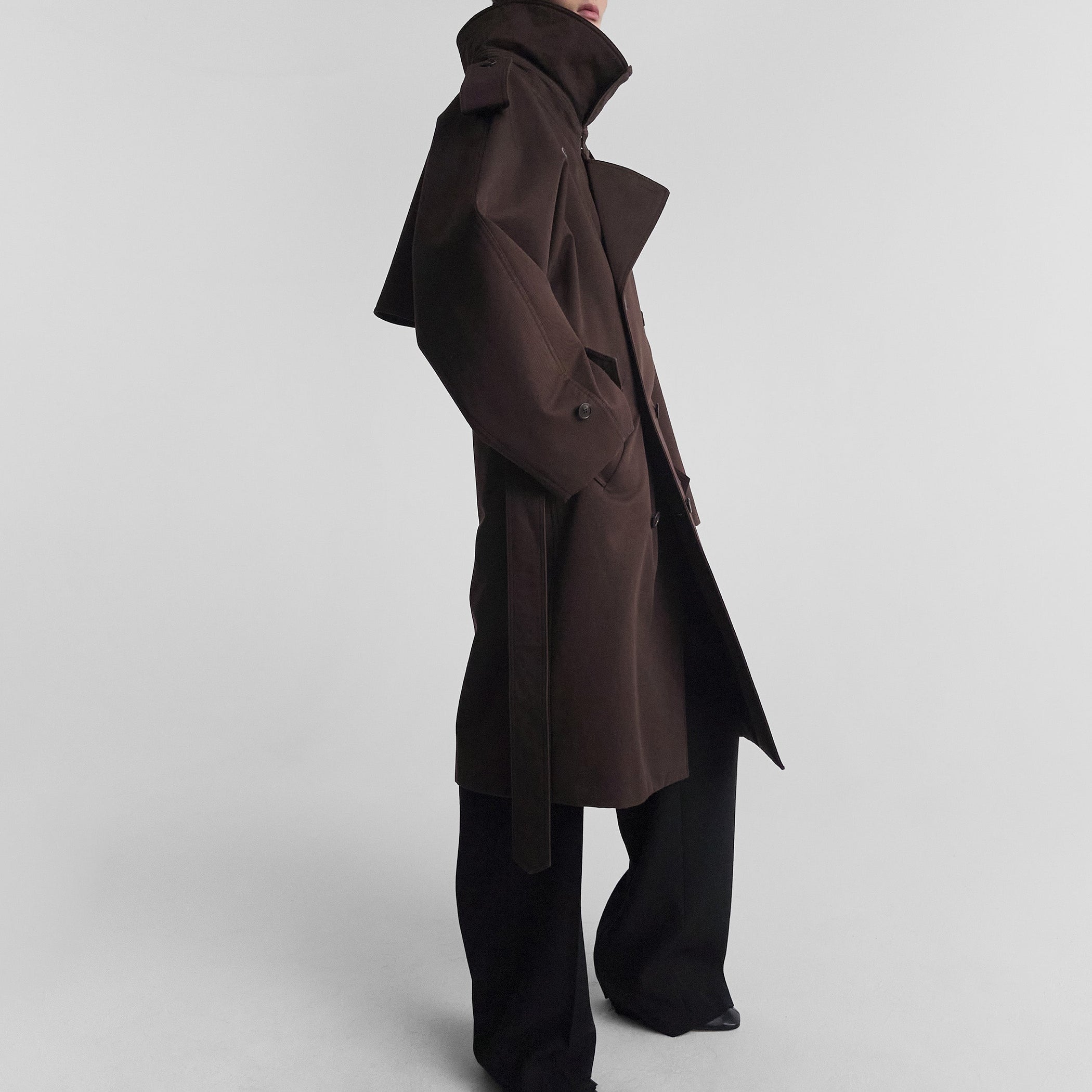 Side view of model wearing PADDED TRENCH COAT in chocolate brown cotton drill
