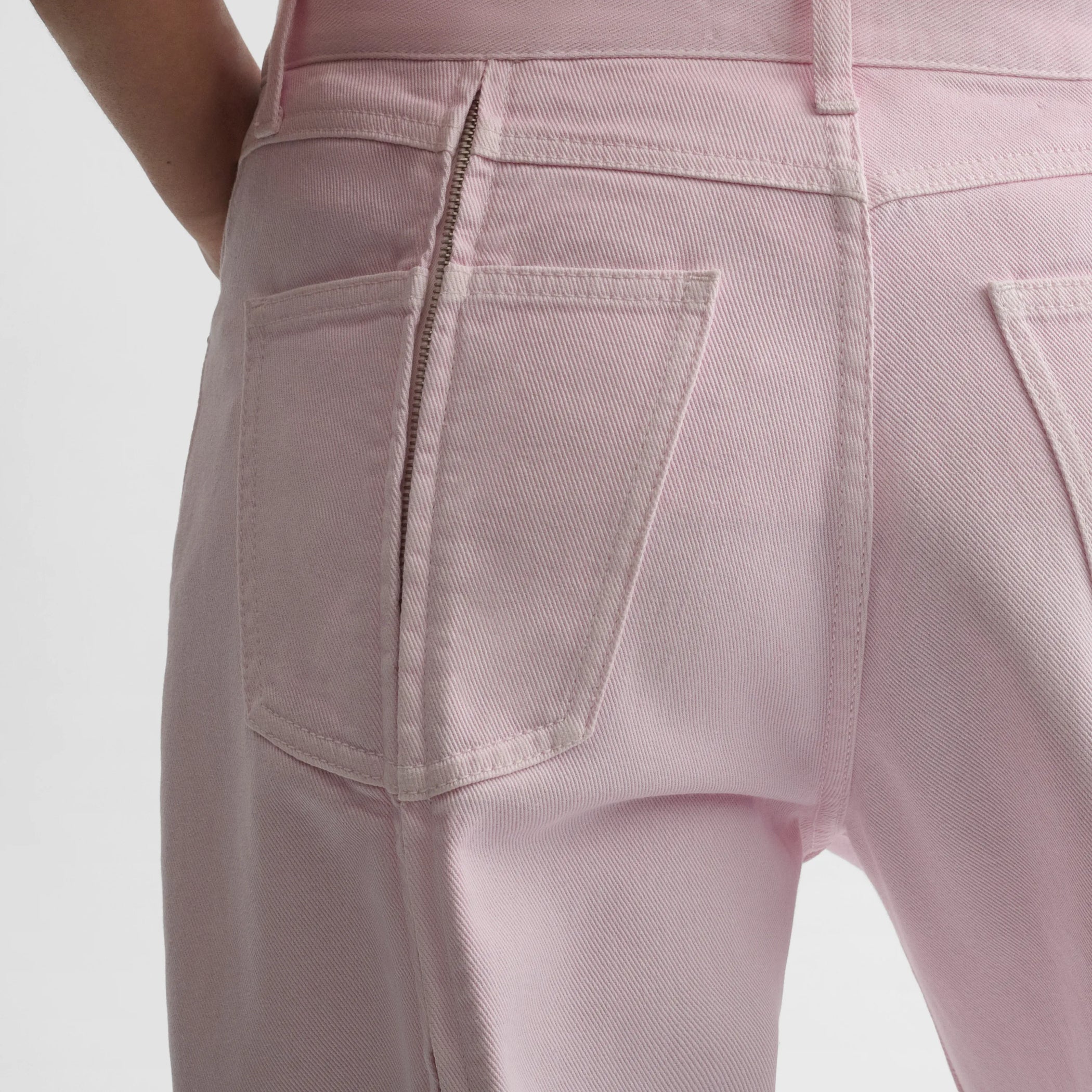 Close up detail view of zip jeans in pale pink cotton