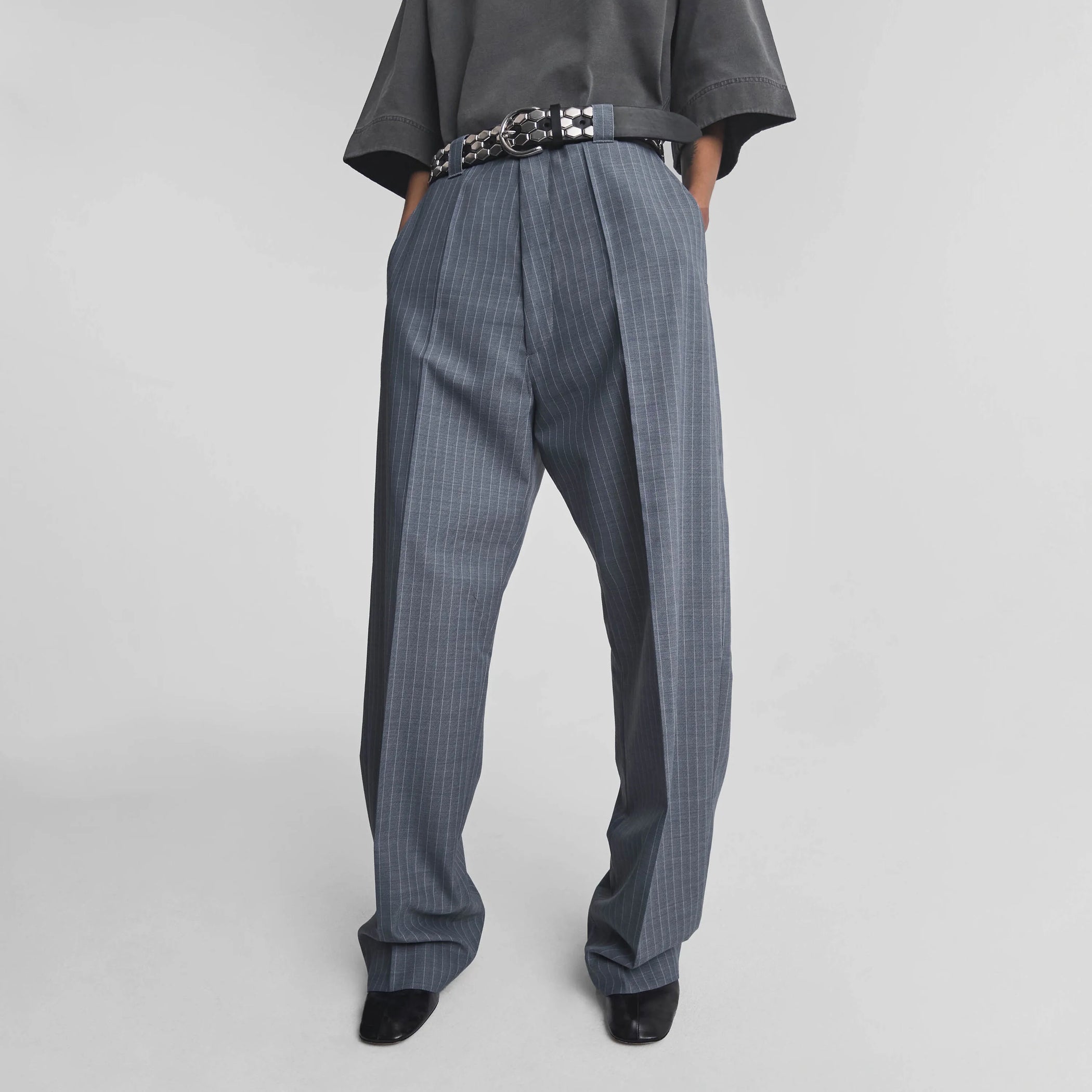 Front view of model wearing OVERSIZED TROUSERS in steel grey pinstripe wool