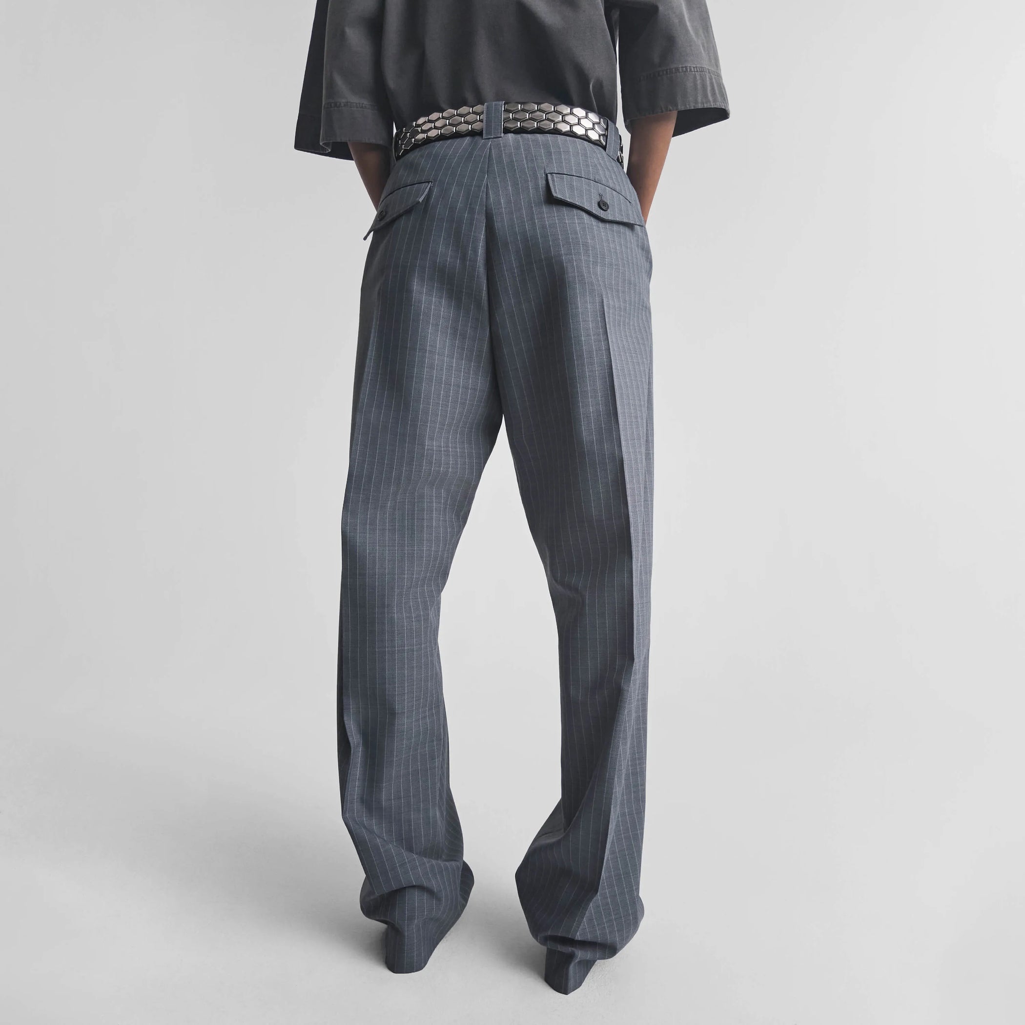 Back view of model wearing OVERSIZED TROUSERS in steel grey pinstripe wool