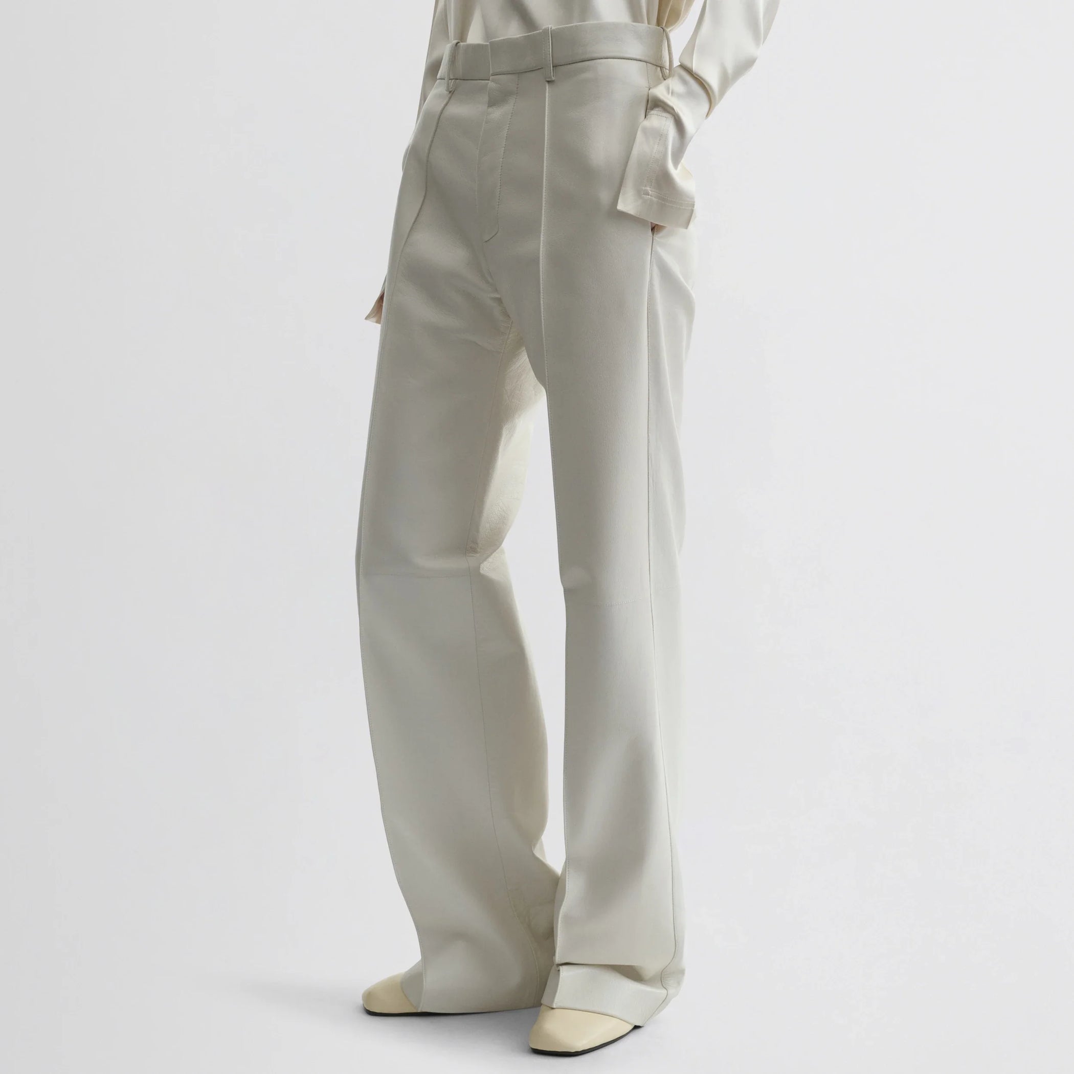 Front view of model wearing boyish trousers in white leather.