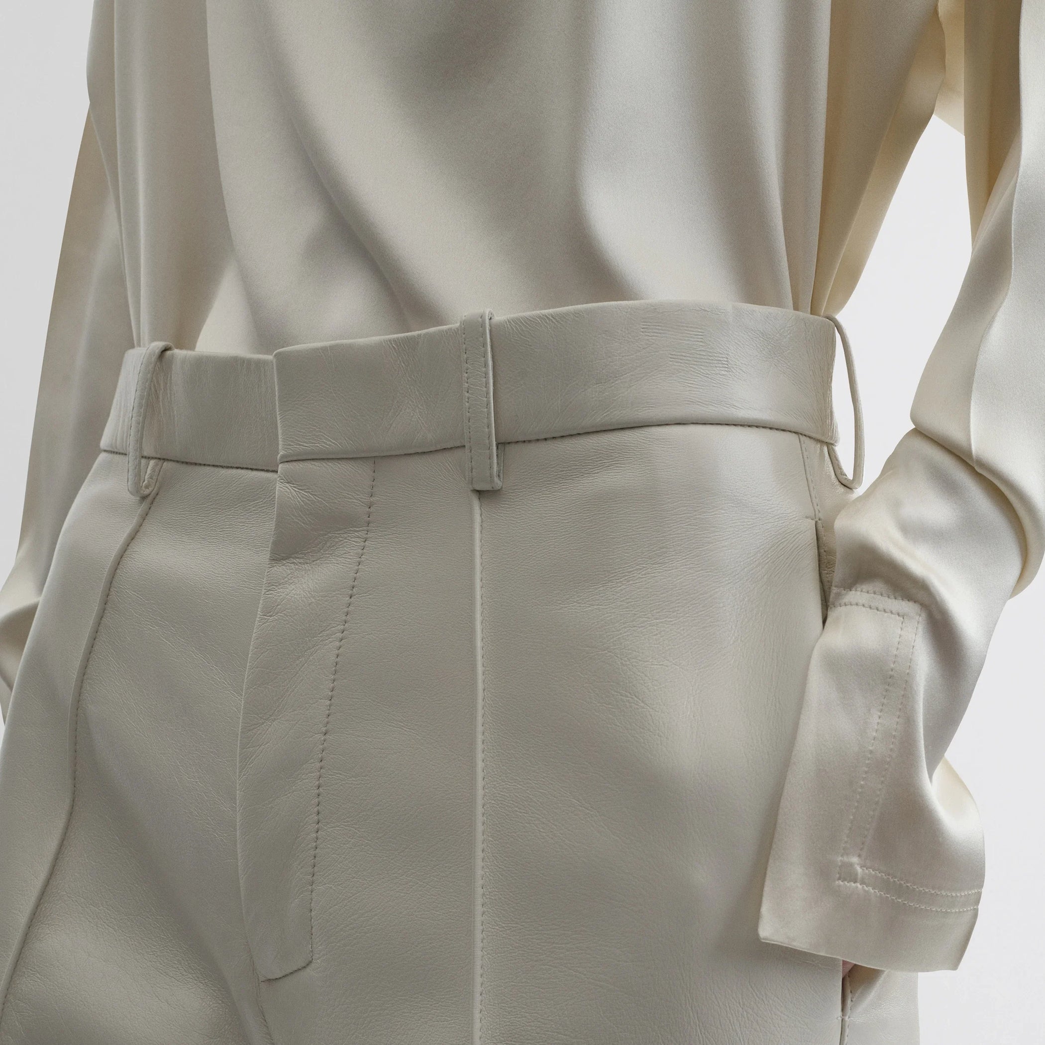 Close up detail view of boyish trousers in white leather.