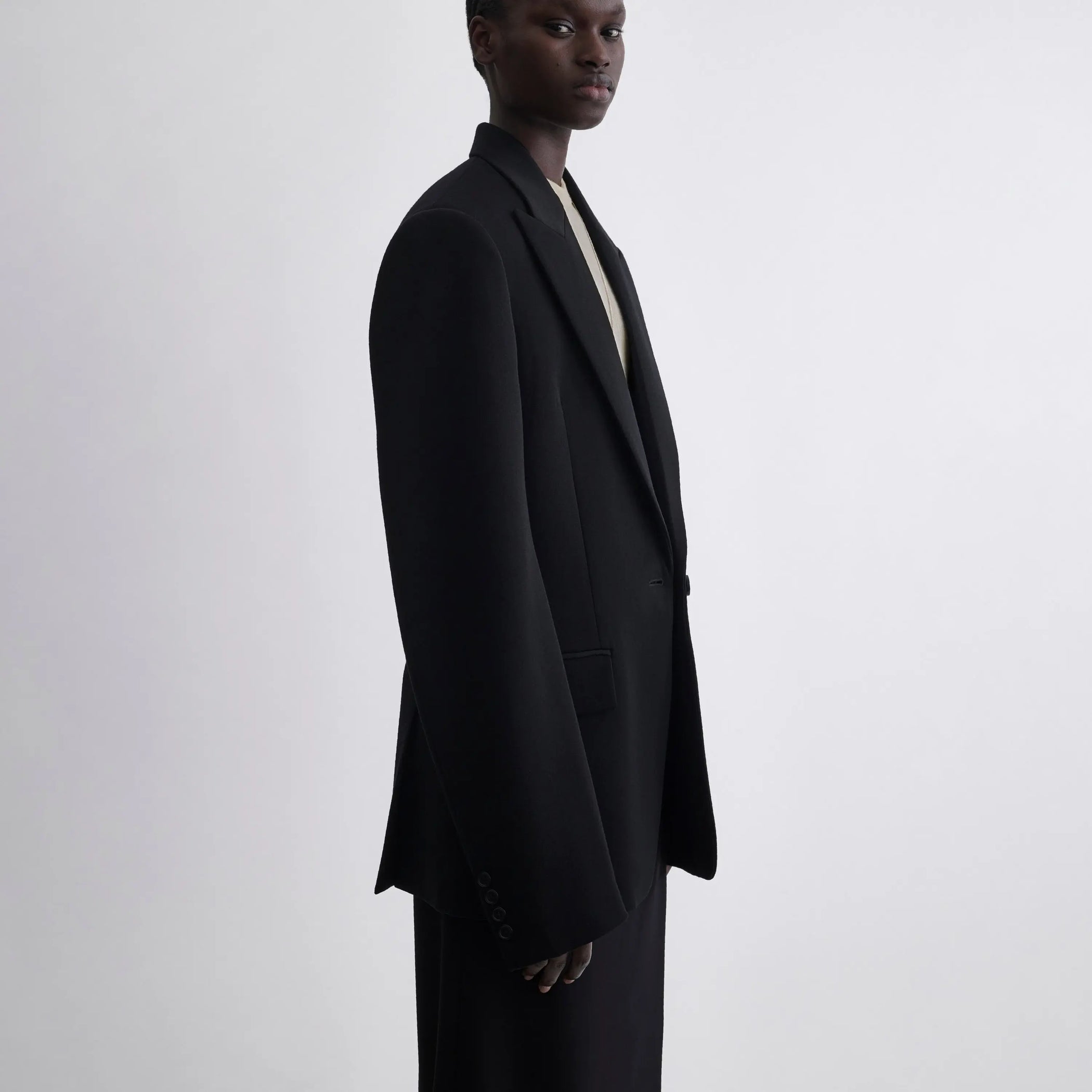 Side view of model wearing Single Breasted Tailored Jacket in black.