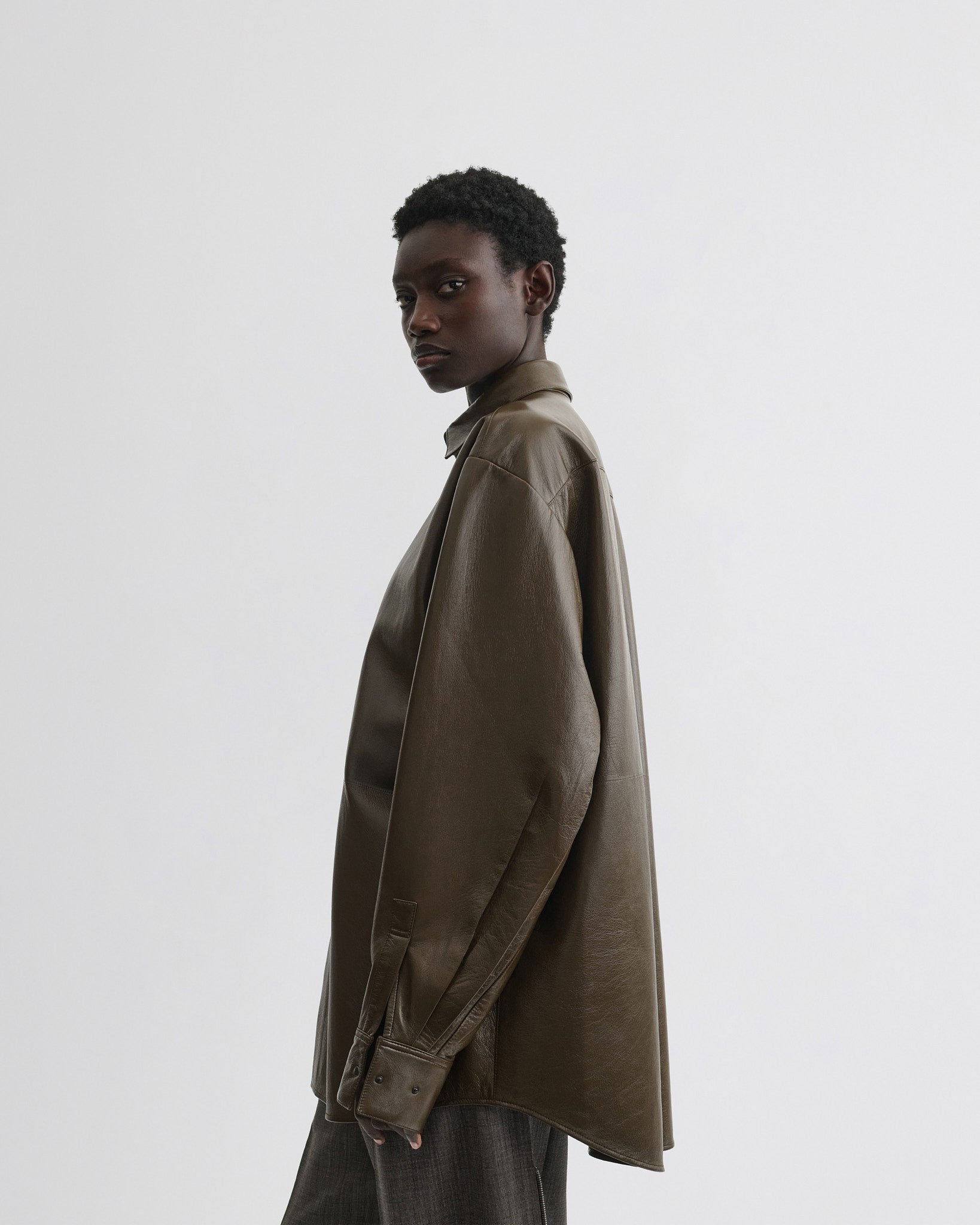 Side view of model wearing overshirt in green bronze leather.