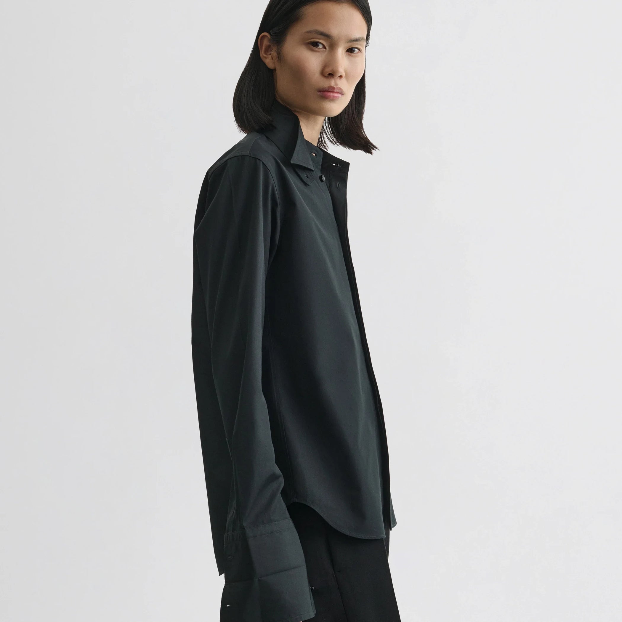 Side view of model wearing tuxedo shirt in black cotton.