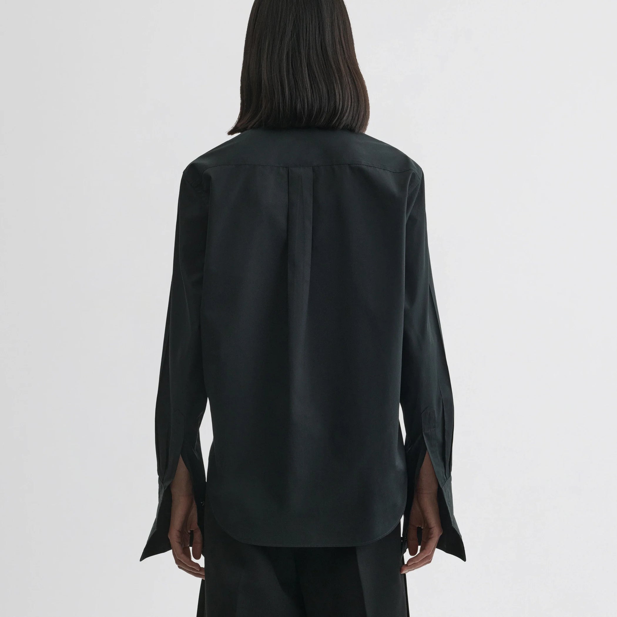 Back view of model wearing tuxedo shirt in black cotton.