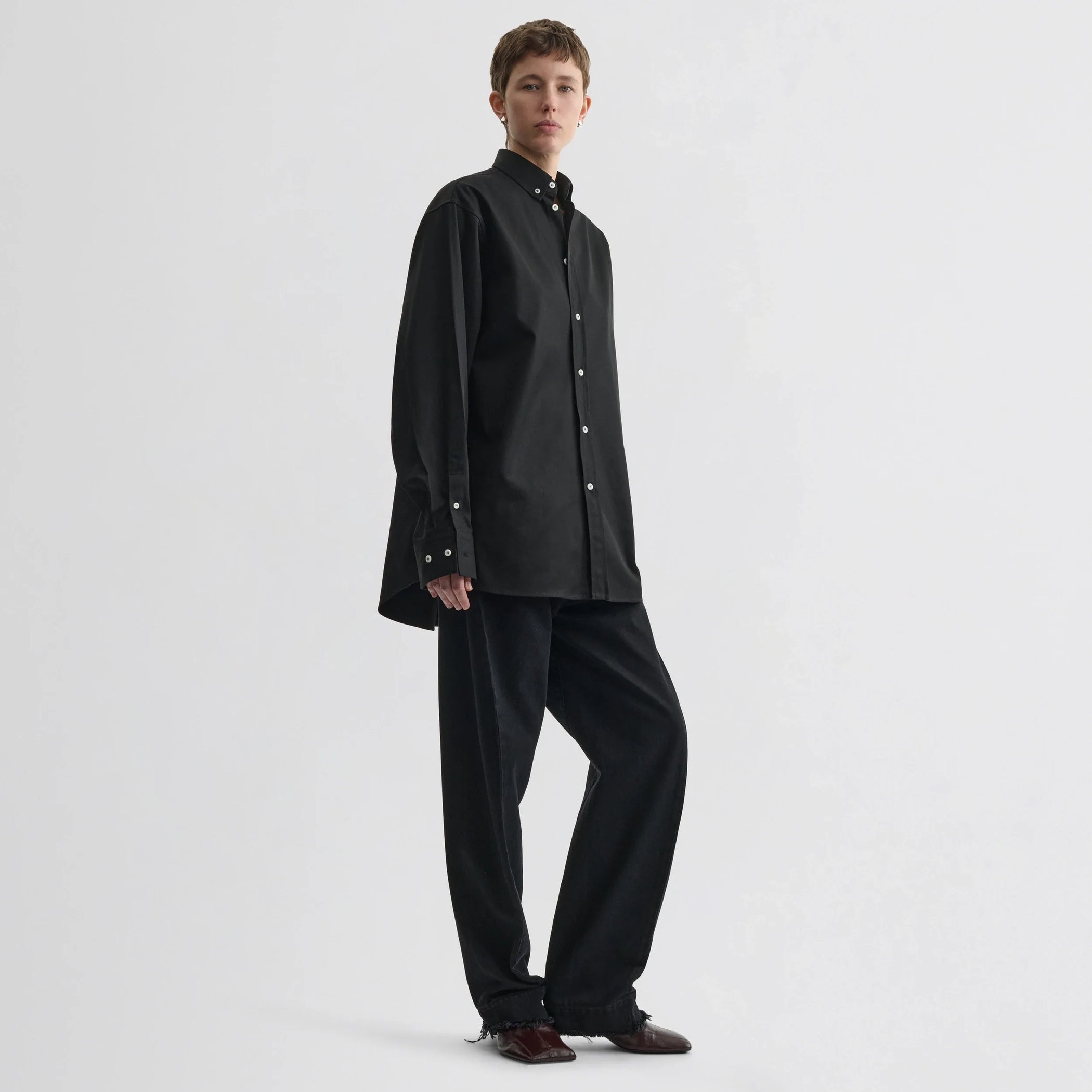 Front view of model wearing button collar shirt in black cotton.