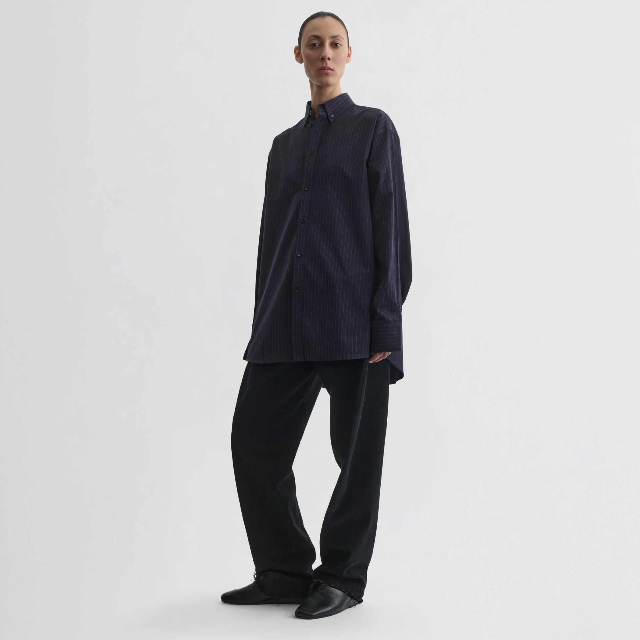 Front view of model wearing button collar shirt in midnight pinstripe cotton.