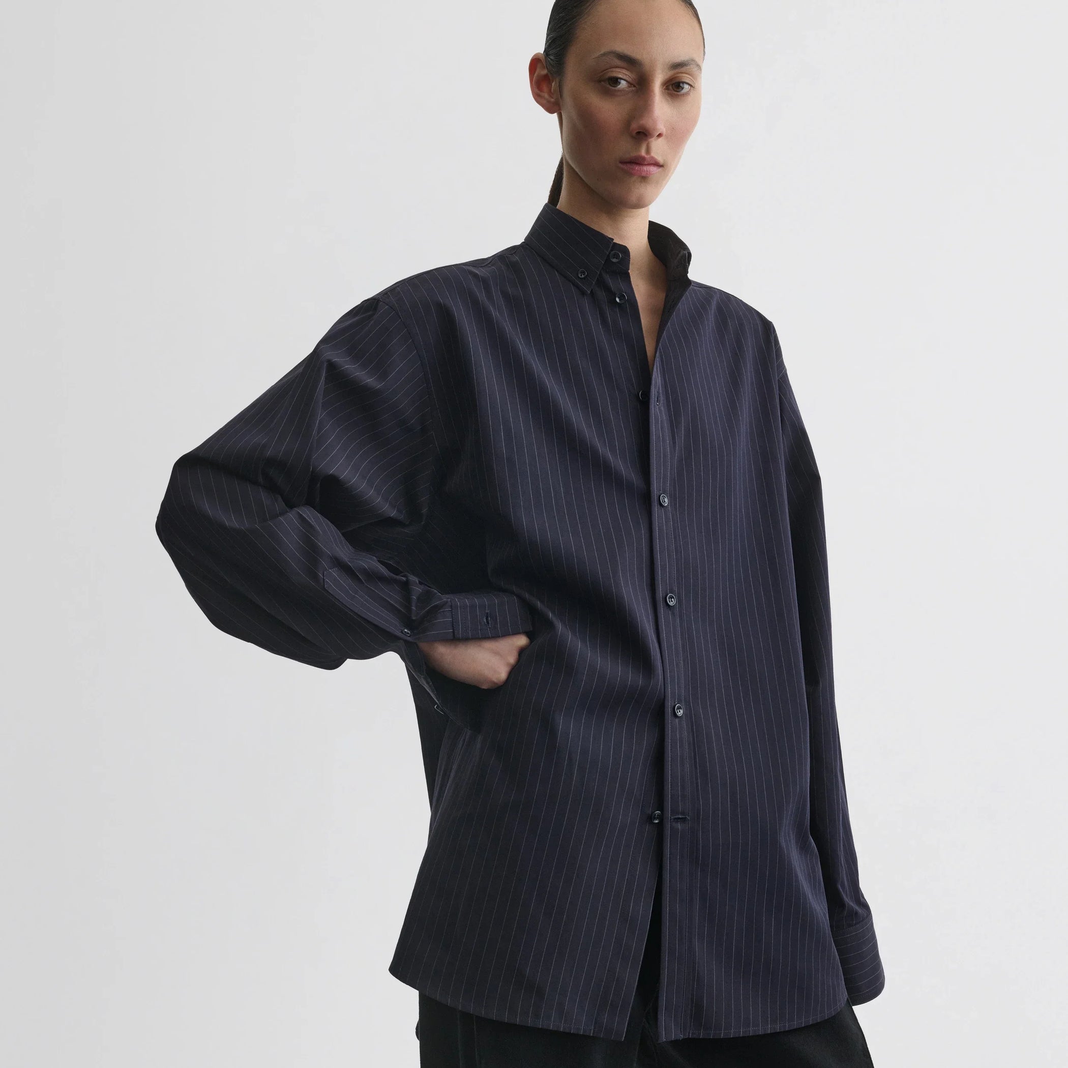 Front view of model wearing button collar shirt in midnight pinstripe cotton.