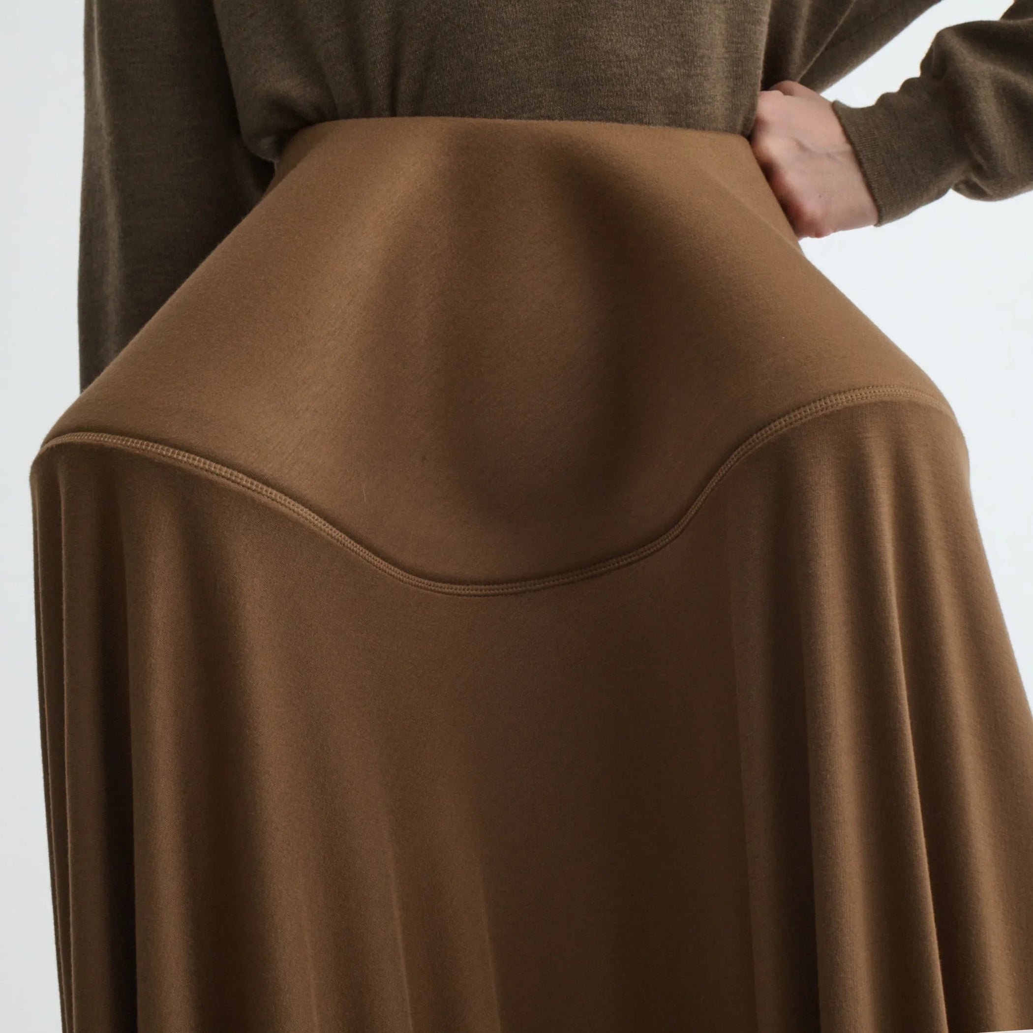 Close up detail view of sculptural skirt in toffee jersey.