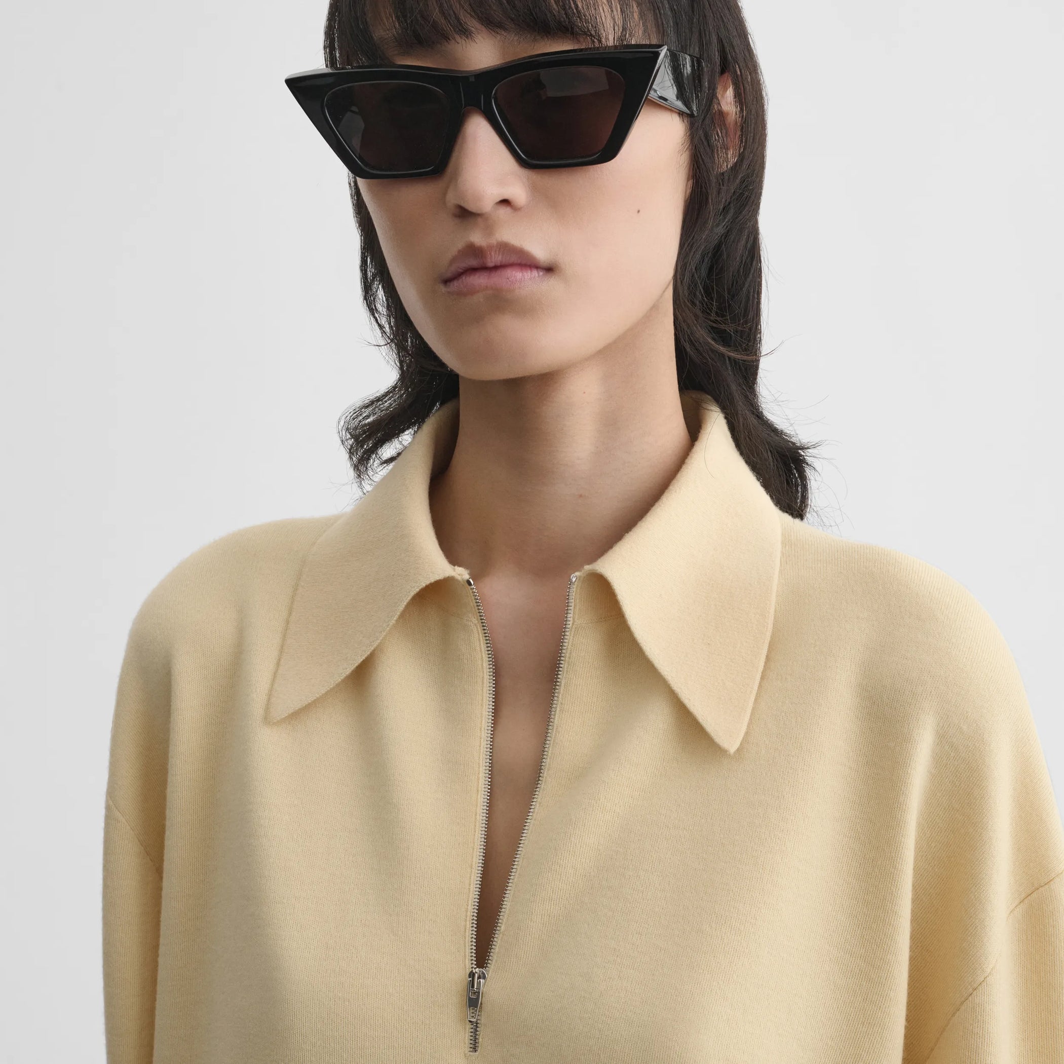 Close up detail view of zip polo in pastel-yellow wool