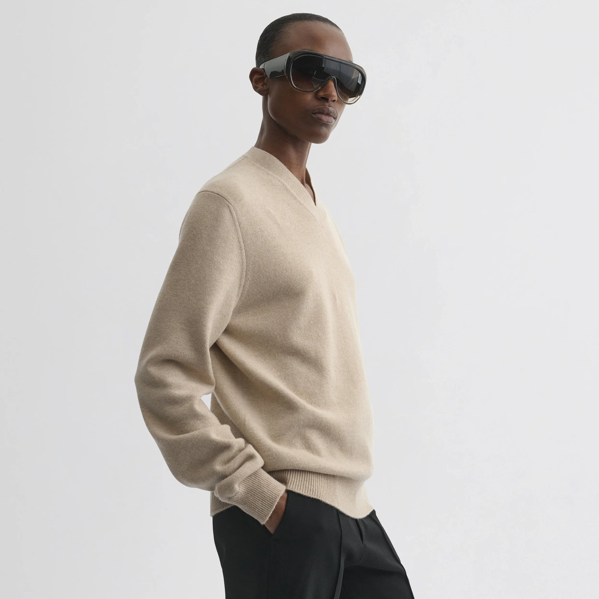 Side view of model wearing easy v-neck sweater in beige wool cashmere.