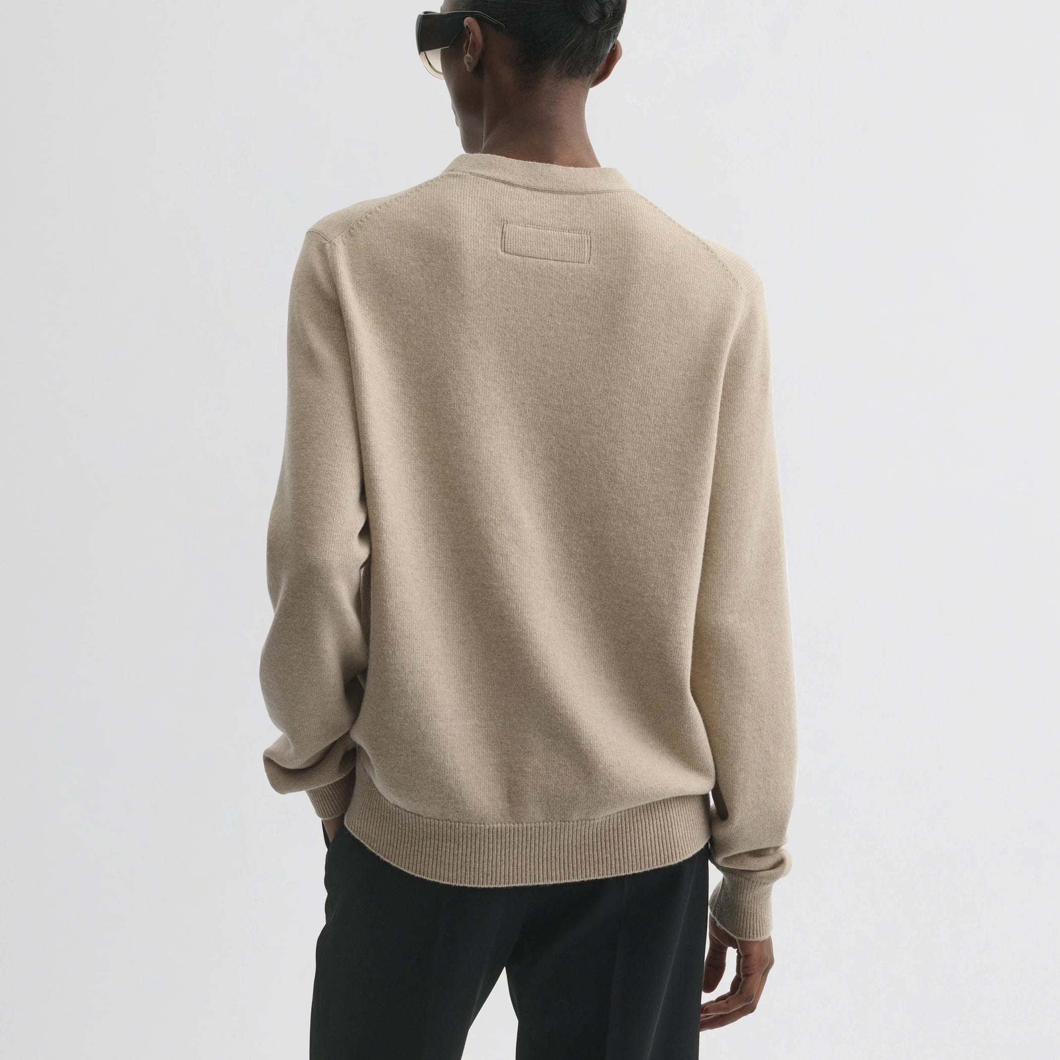 Back view of model wearing easy v-neck sweater in beige wool cashmere.