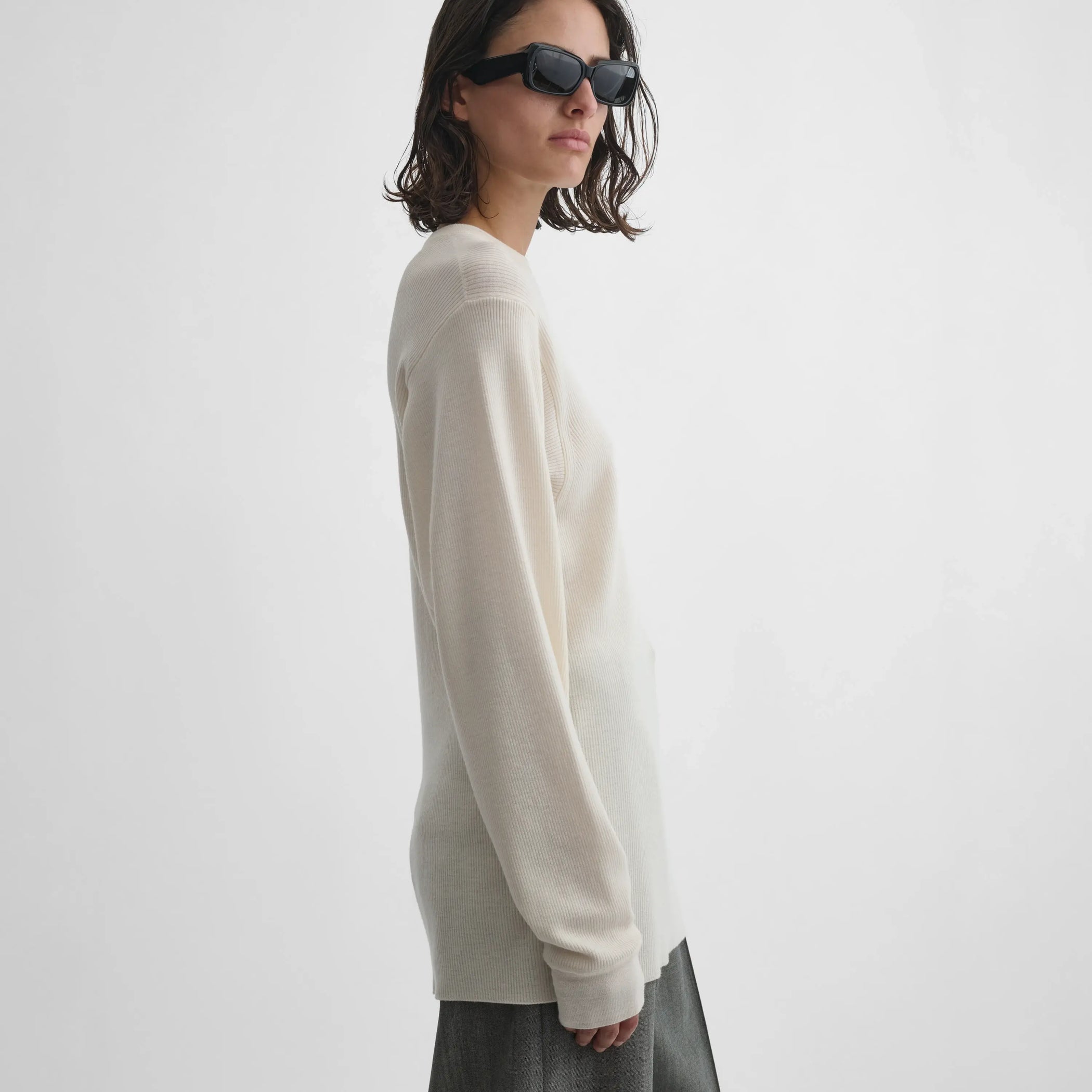 Side view of model wearing Ribbed Long Sleeve Crewneck in cream.