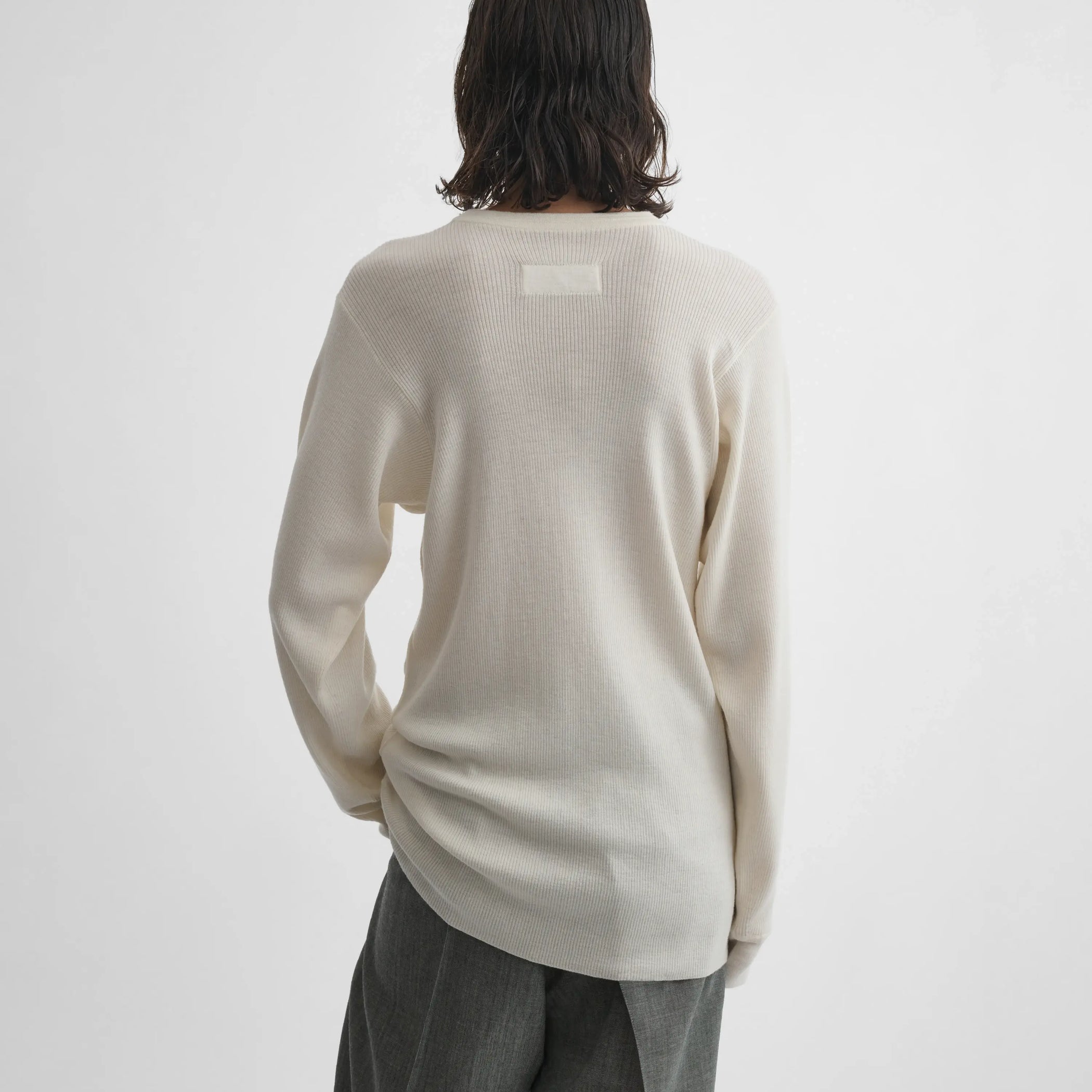 Back view of model wearing Ribbed Long Sleeve Crewneck in cream.