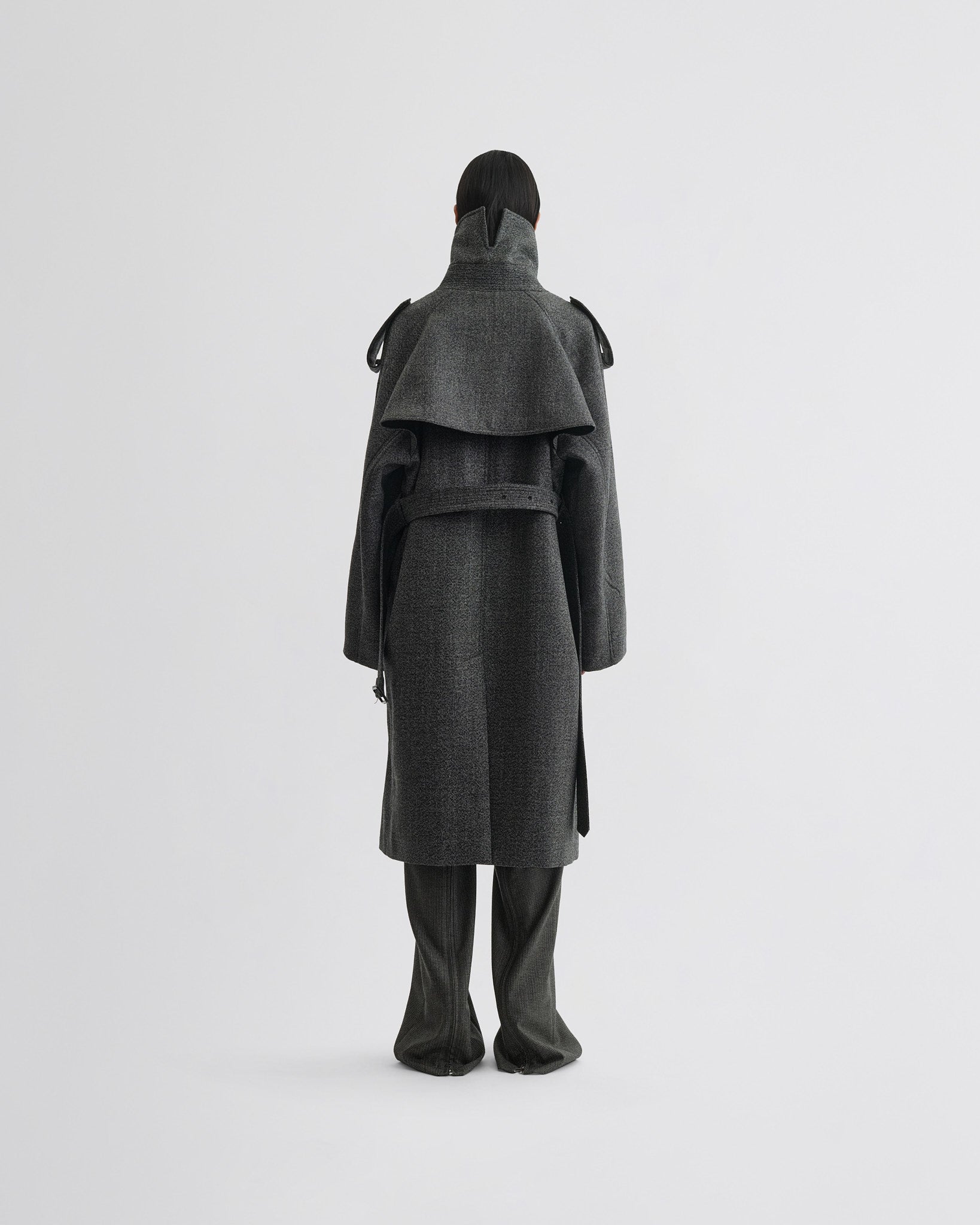 Back view of model wearing padded trench coat in salt and pepper wool.