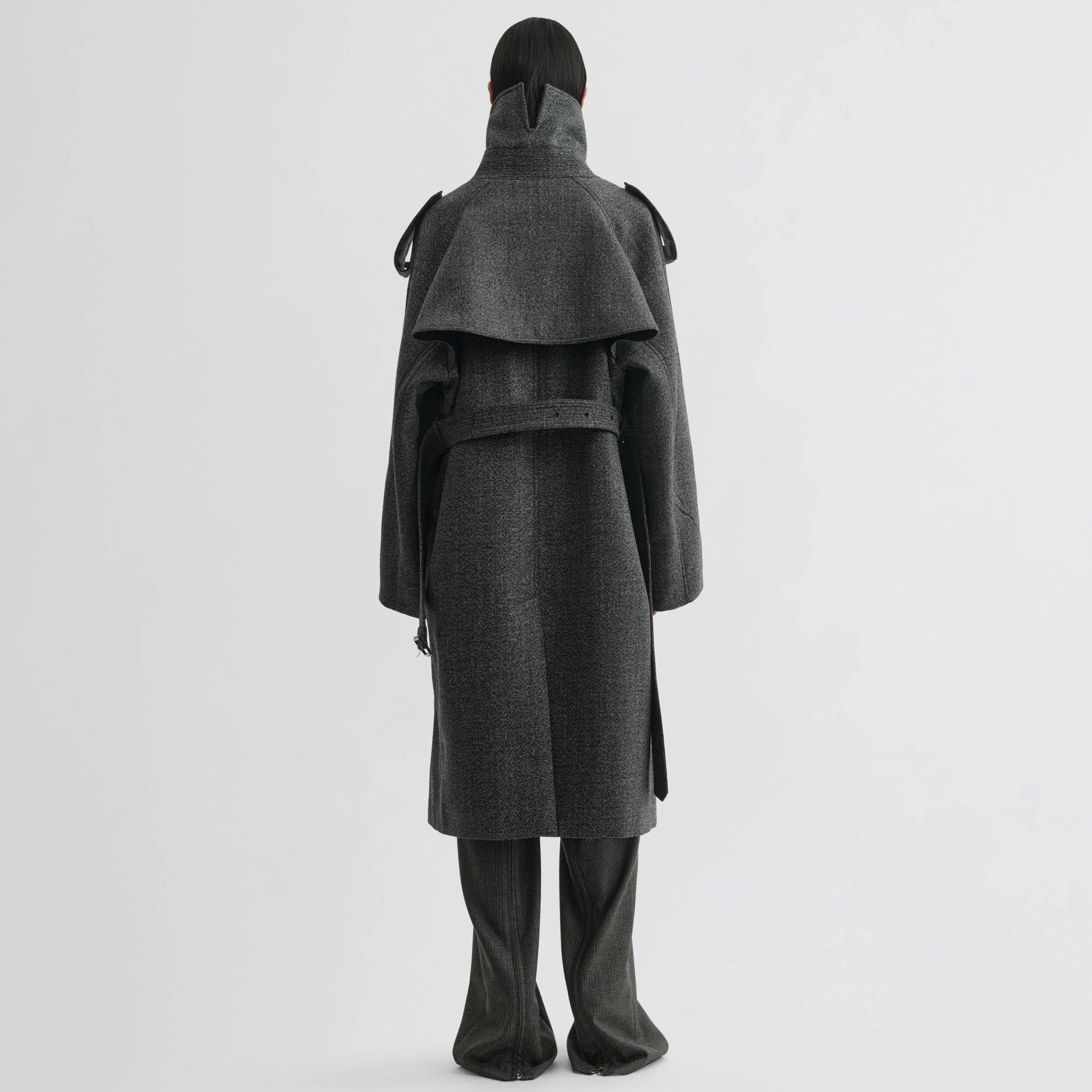 Back view of model wearing padded trench coat in salt and pepper wool.