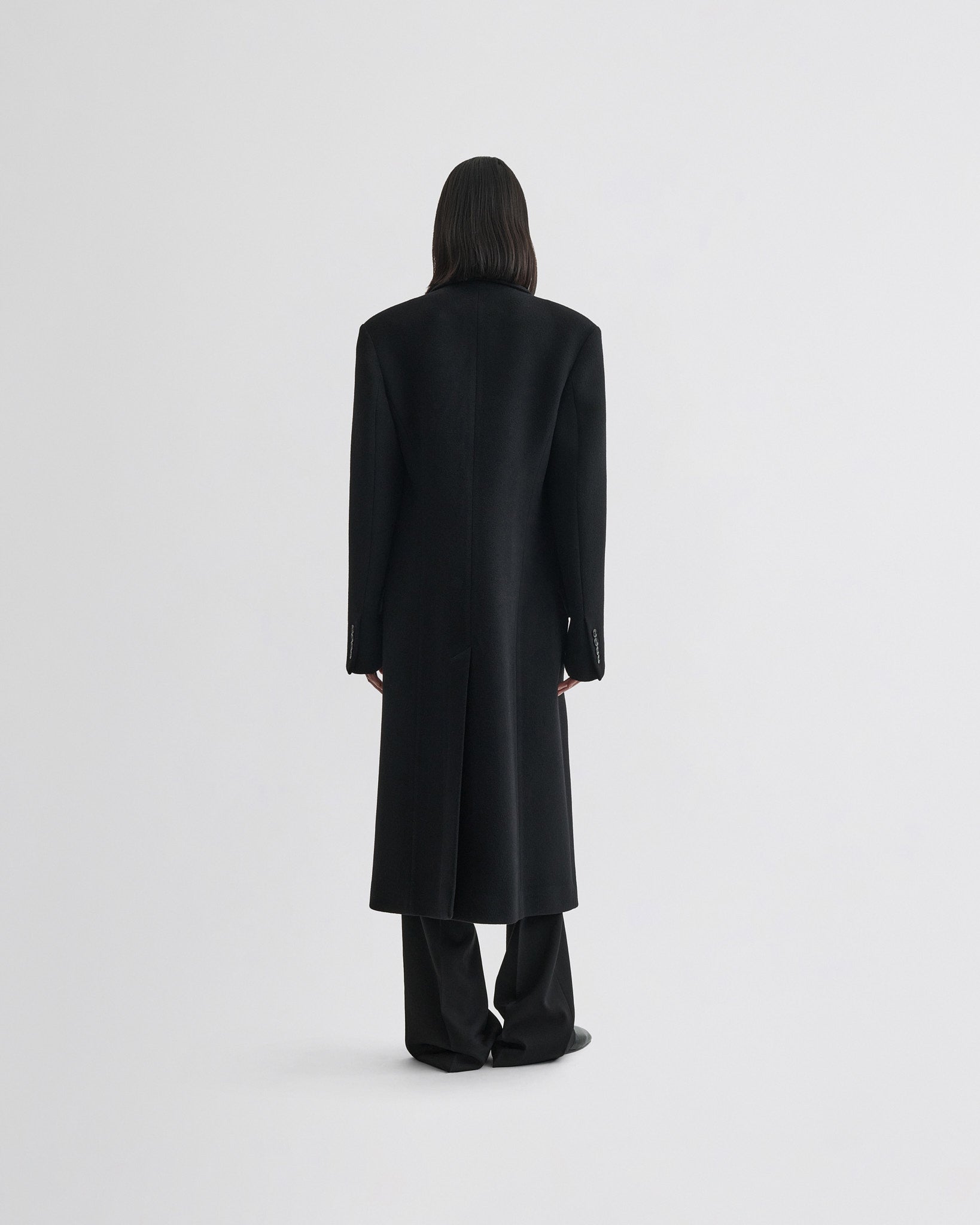 Back view of model wearing classic coat in black cashmere.
