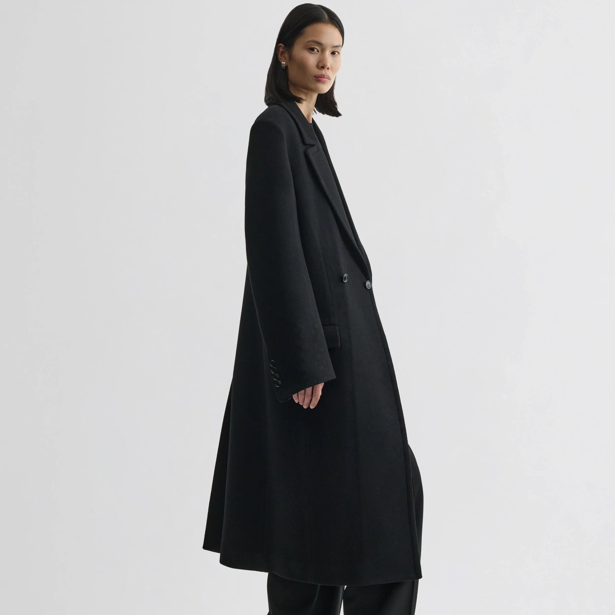 Side view of model wearing classic coat in black cashmere.
