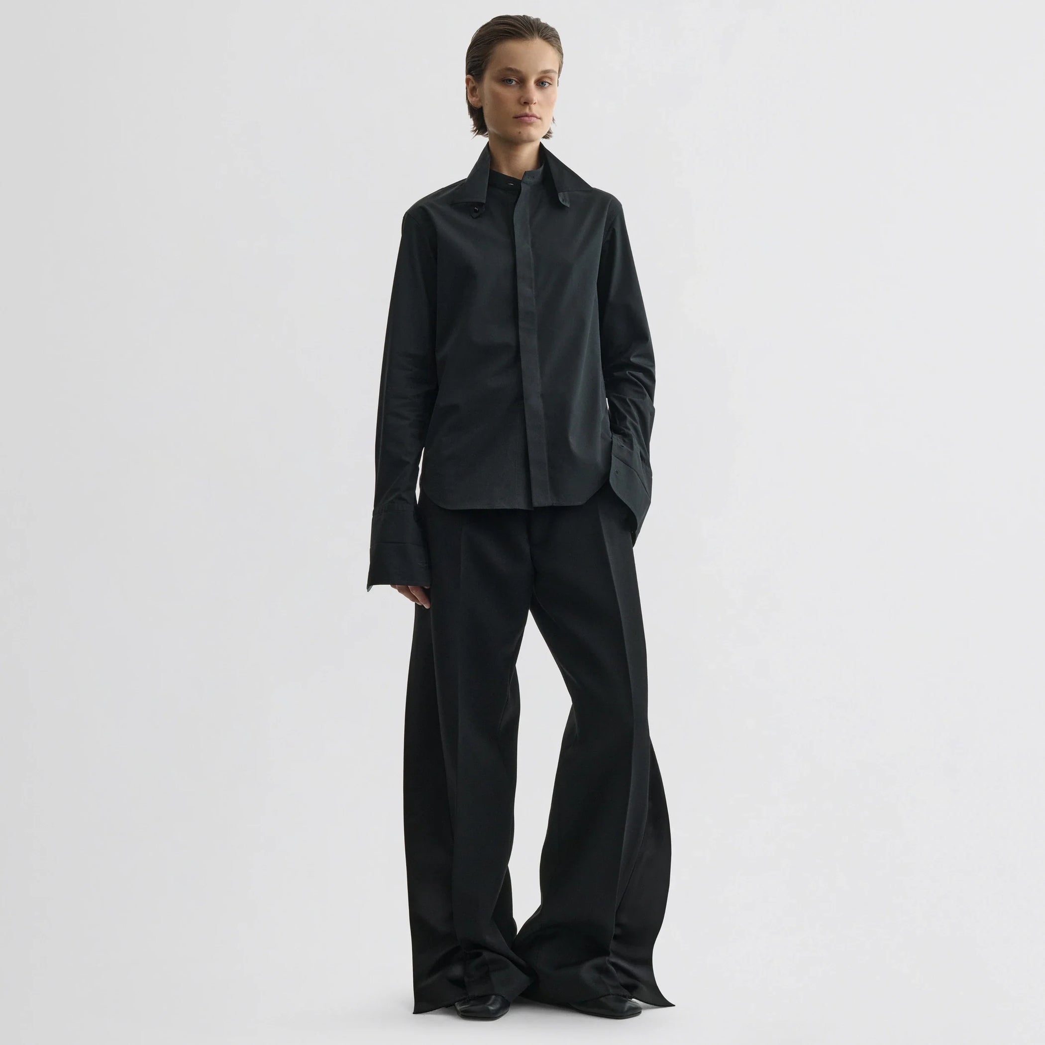 Front view of model wearing split tux trousers in black wool.