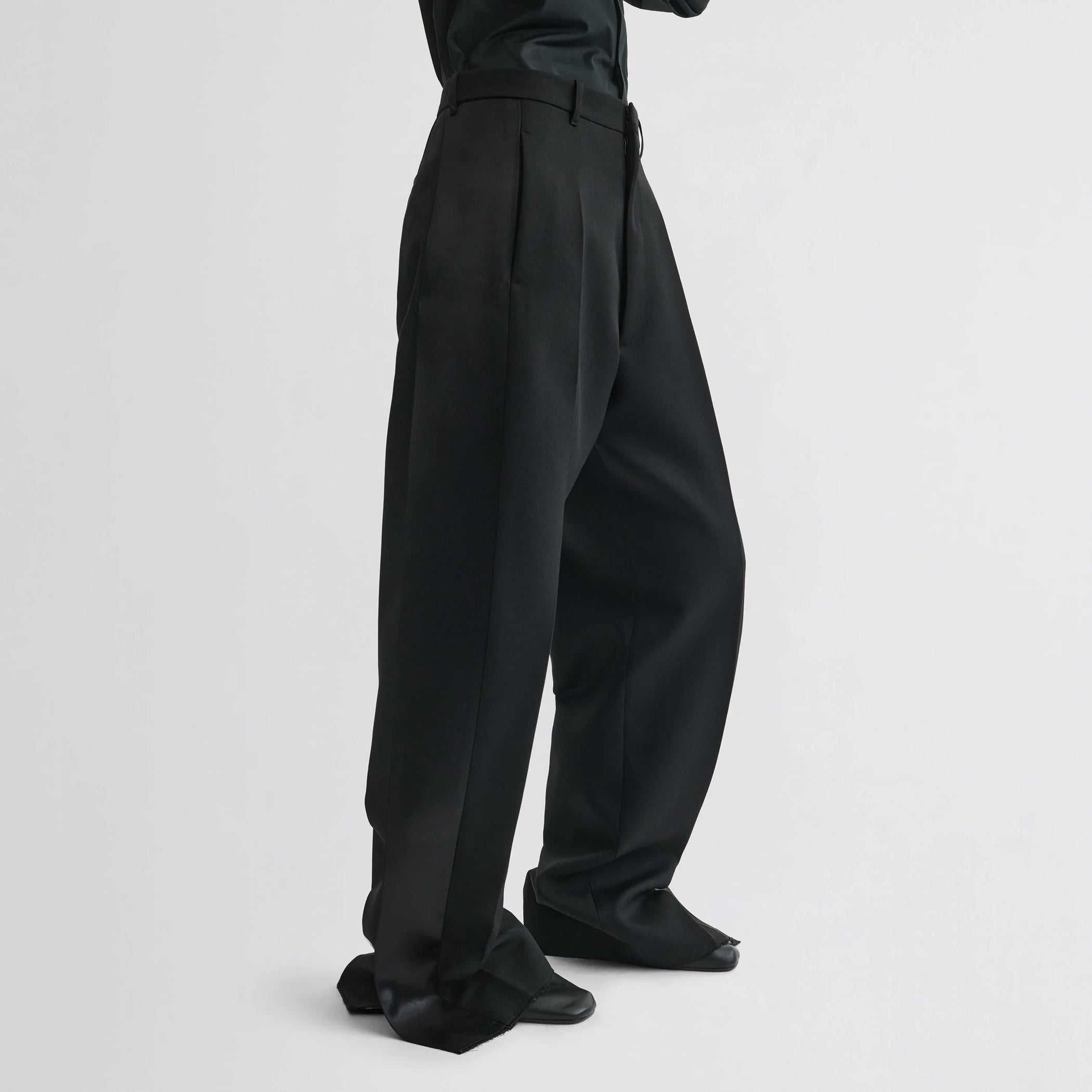 Side view of model wearing split tux trousers in black wool.