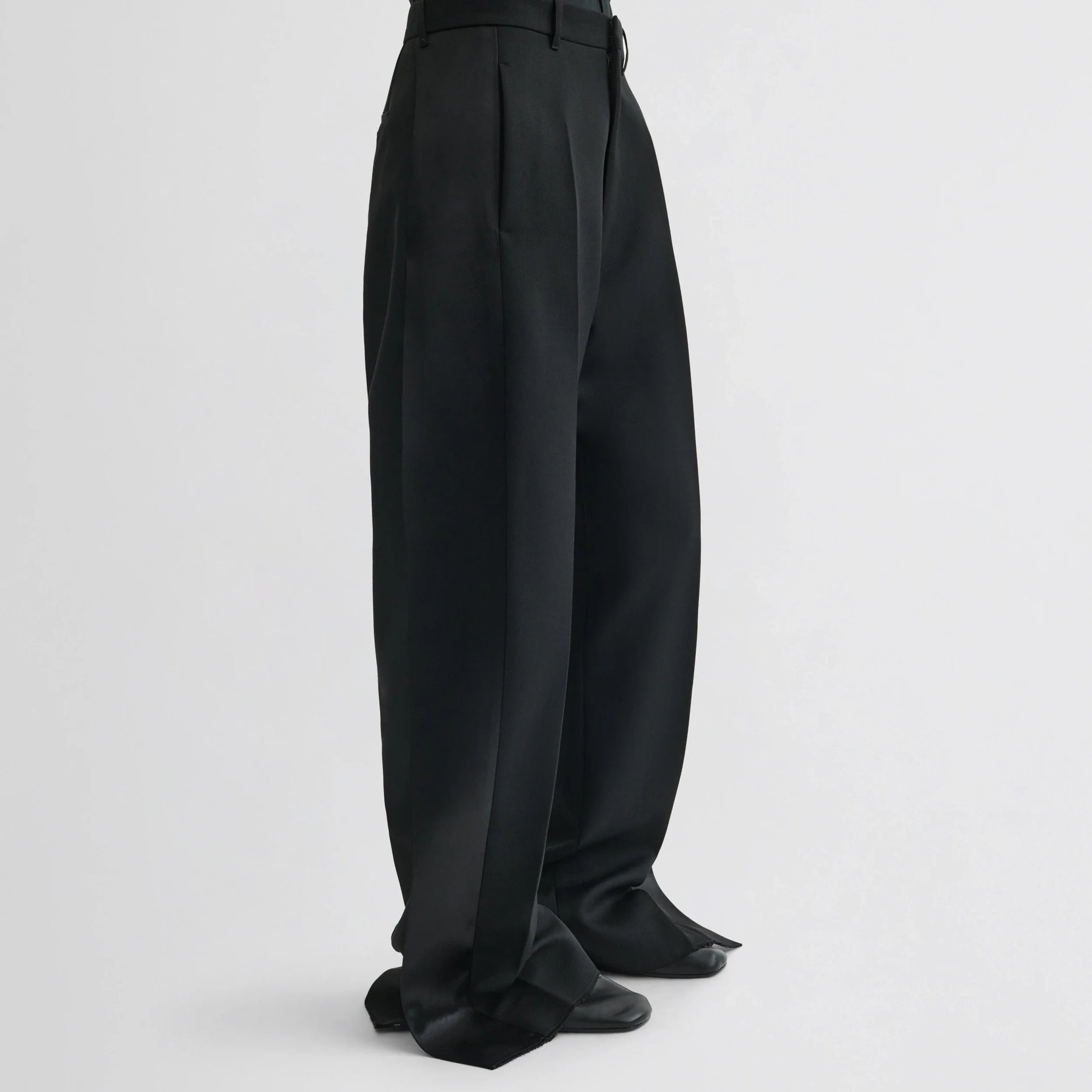 Side view of model wearing split tux trousers in black wool.
