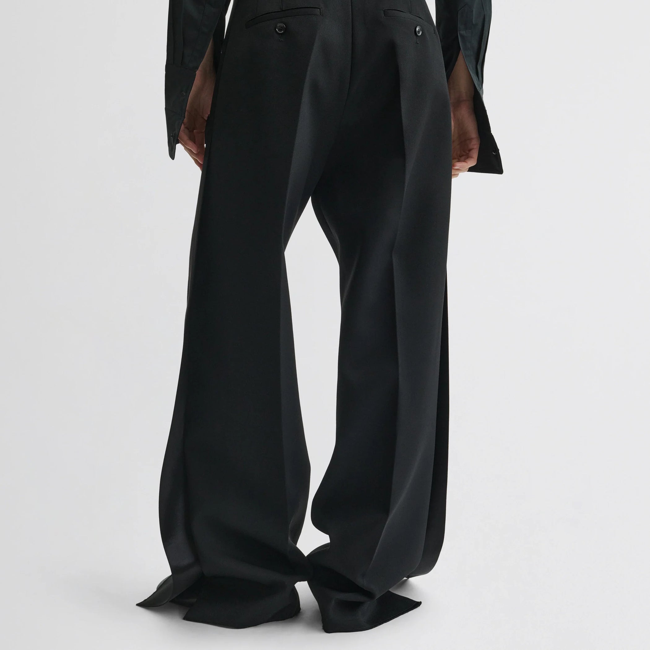 Back view of model wearing split tux trousers in black wool.