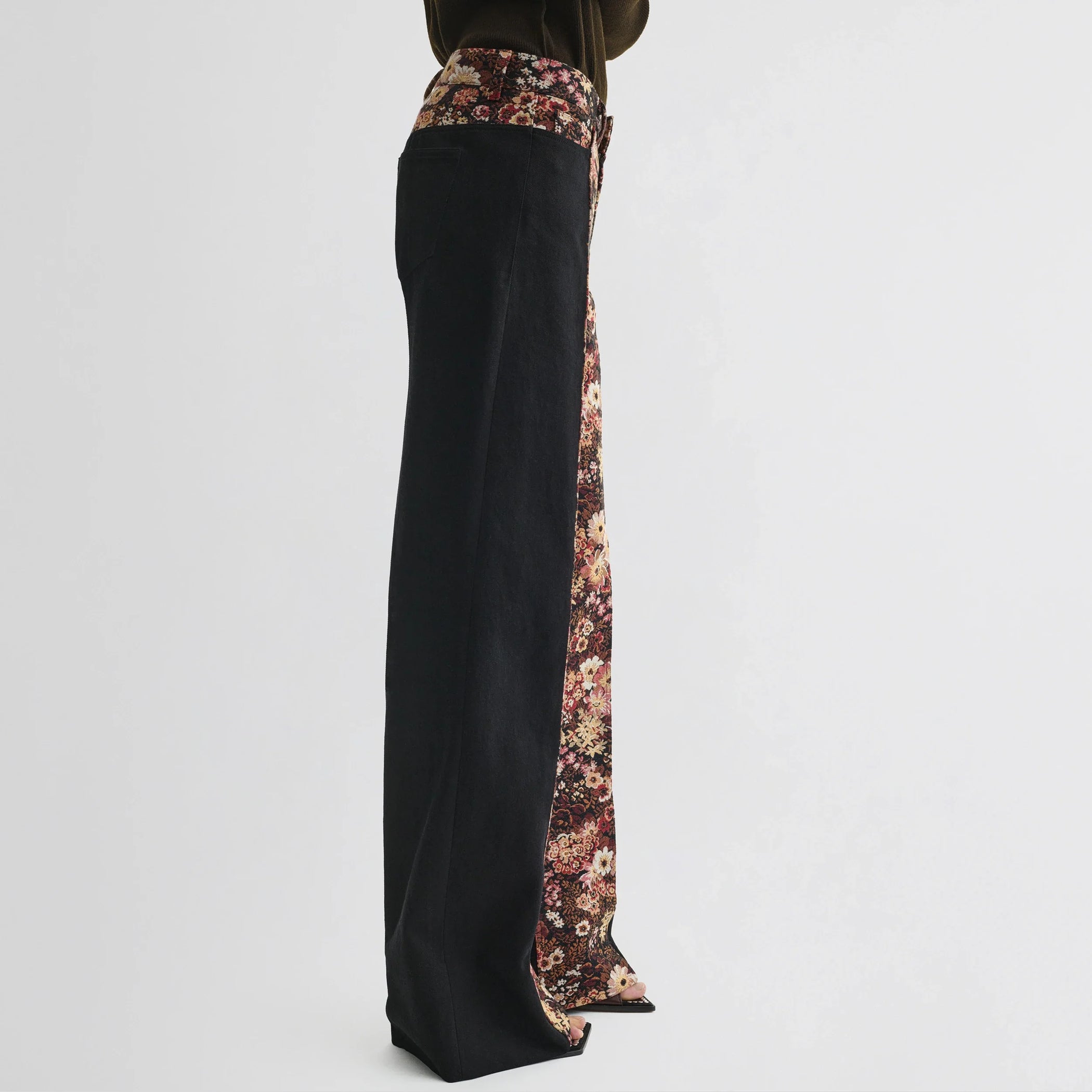 Side view of model wearing tapestry trousers in black cotton.